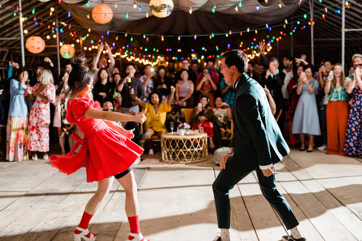 The bride and groom show their dance moves during their first dance in front of cheering wedding guests at the unique wedding venue Dos Pueblos Orchid Farm.
