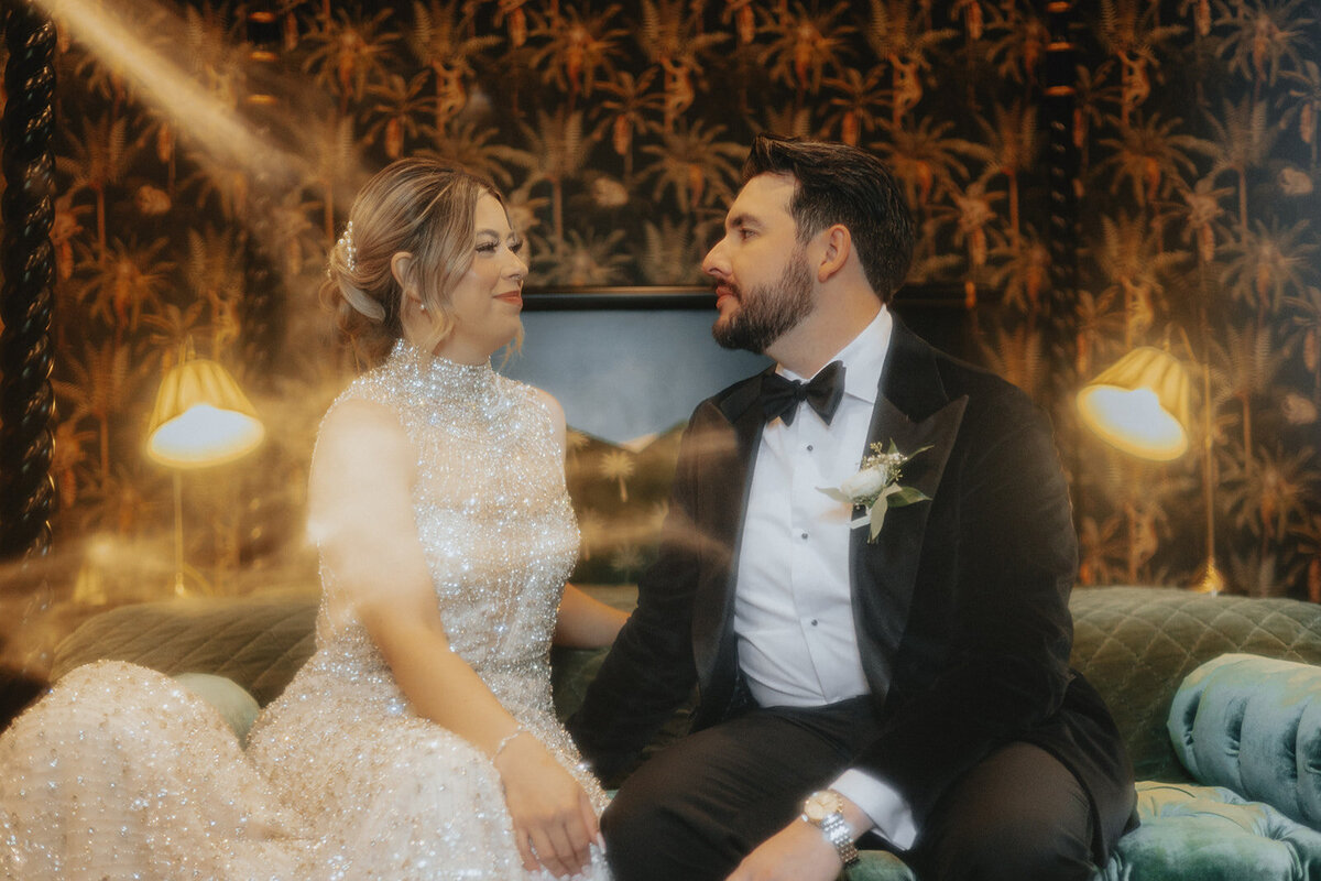 Bride and groom smiling at each other on bed