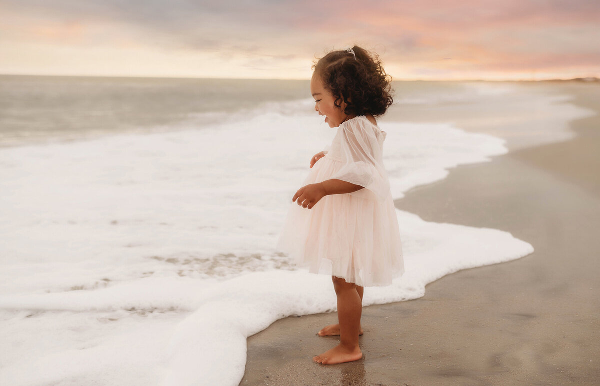 Baby plays in the ocean on Isle of Palms during her Milestone Baby Photoshoot in Charleston, SC.