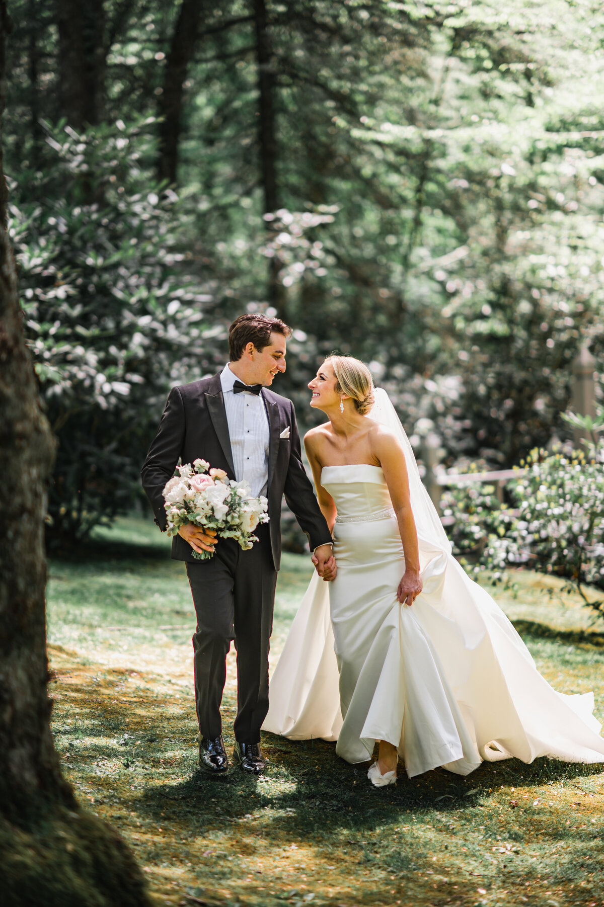 Bride and groom holding hands while walking through the garden pathways at Old Edwards Inn in Highlands, North Carolina.