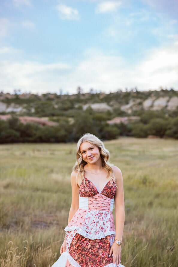 Girl smiles sweetly with mountains behind her.