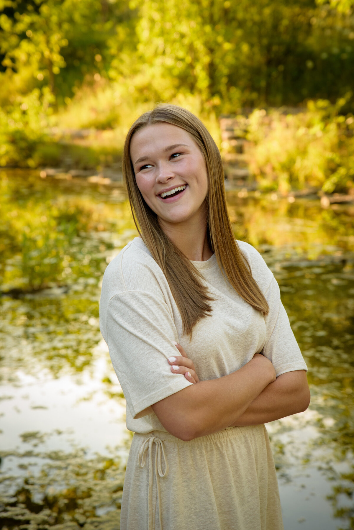 Teenage girl with long blonde hair and a cream colored dress standing near the creek at Fonferek Glen County Park near Green Bay, Wisconsin