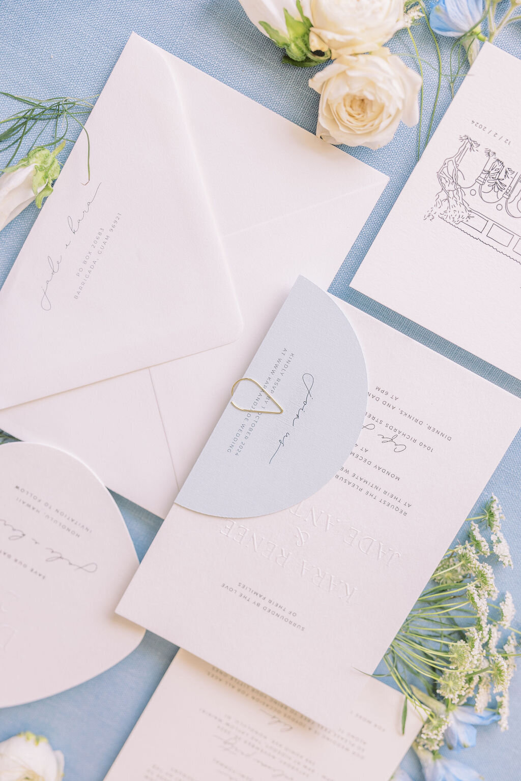 invitation suite with blue and white coloring on a blue backdrop flat lay detail wedding shot