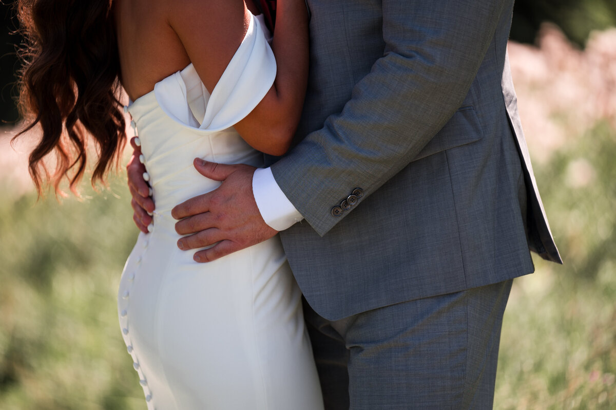 close up of the groom pulling his bride in by the waist