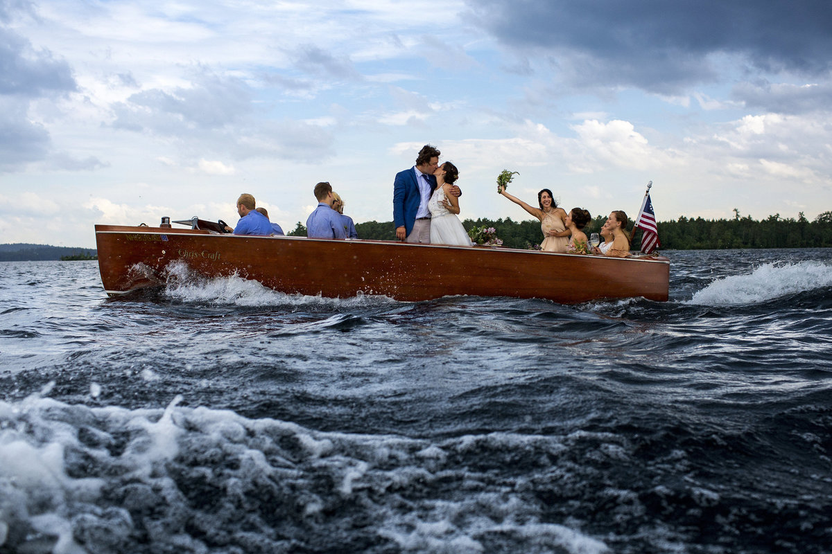 Squam Lake New Hampshire Wedding Photographer the bride and groom out on the stormy waters in a boat as they head back to mainland from their ceremony.