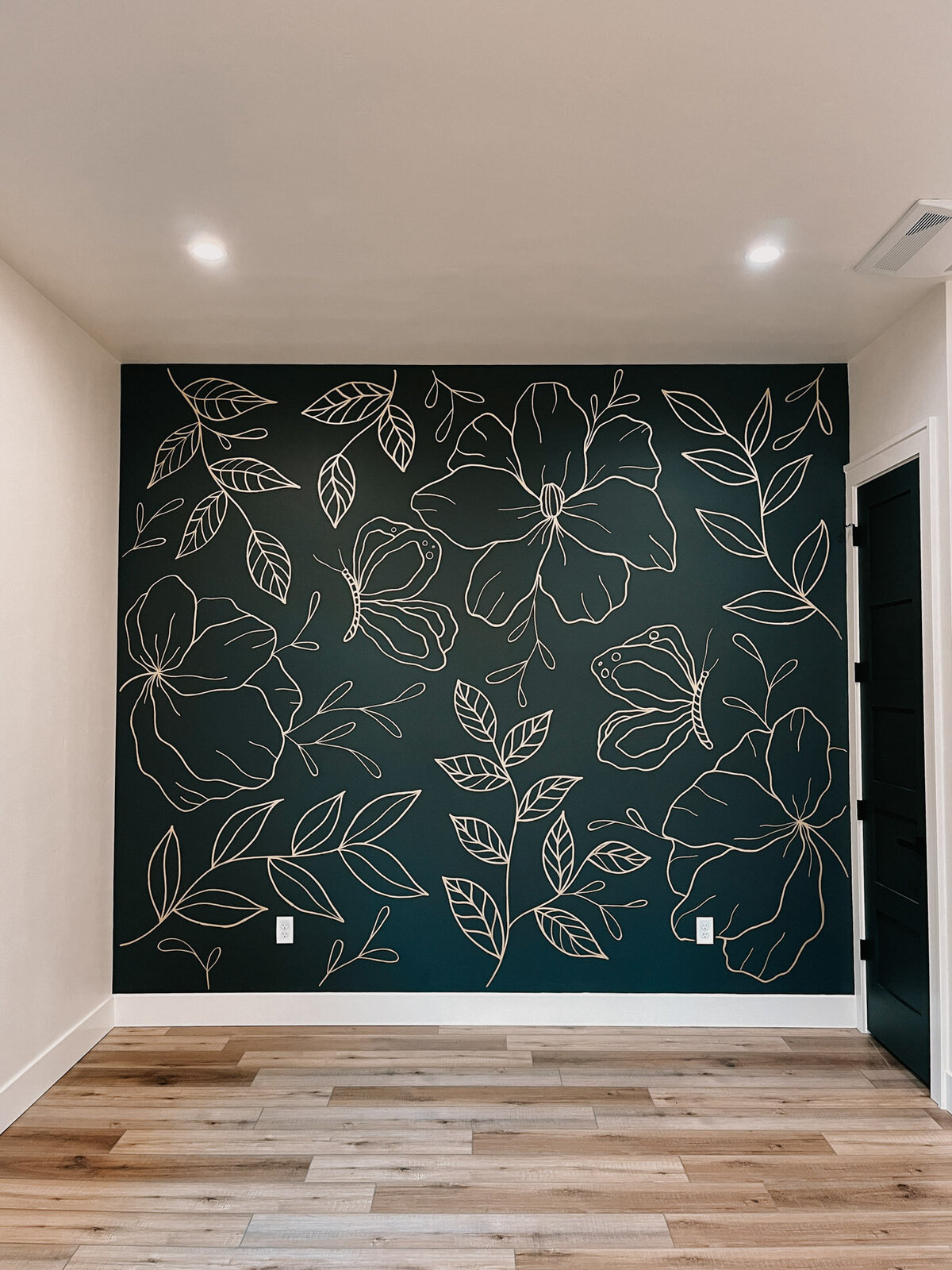 A home office wall in black with modern florals hand-drawn on it in gold representing full service design and calligraphy by Life in Letters.