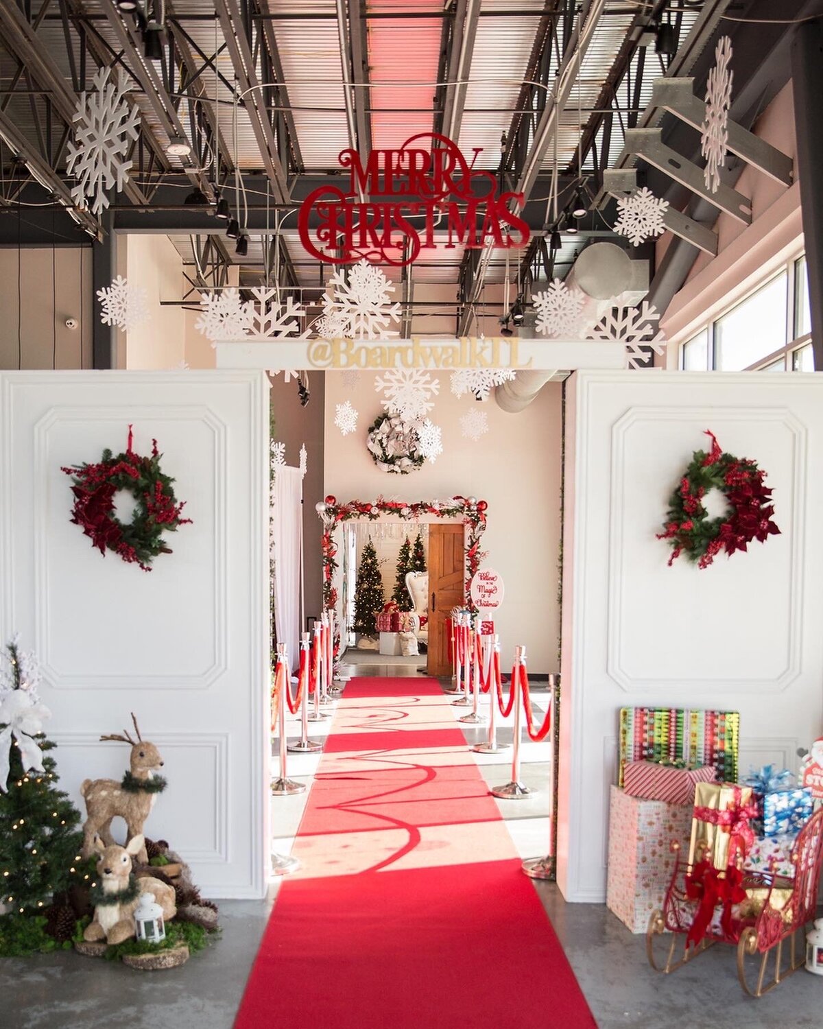 Holiday themed red carpet event display with white backdrops decorated with wreaths