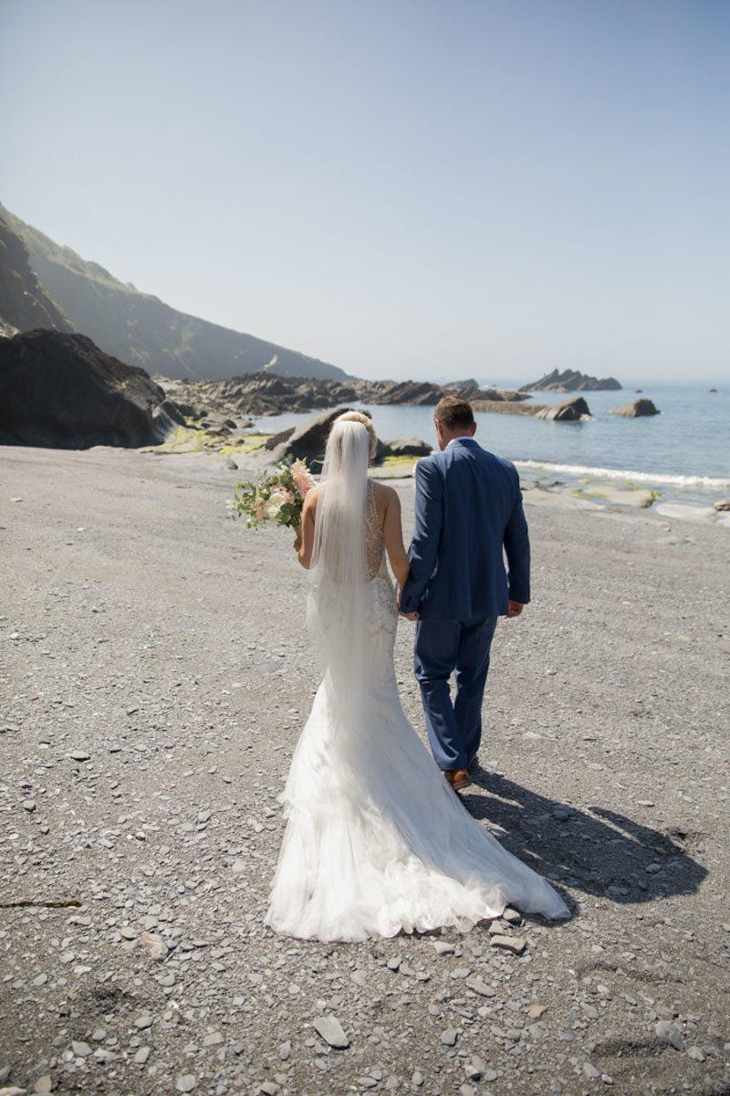 Back view of Bride & Groom walking away at Tunnels Beaches