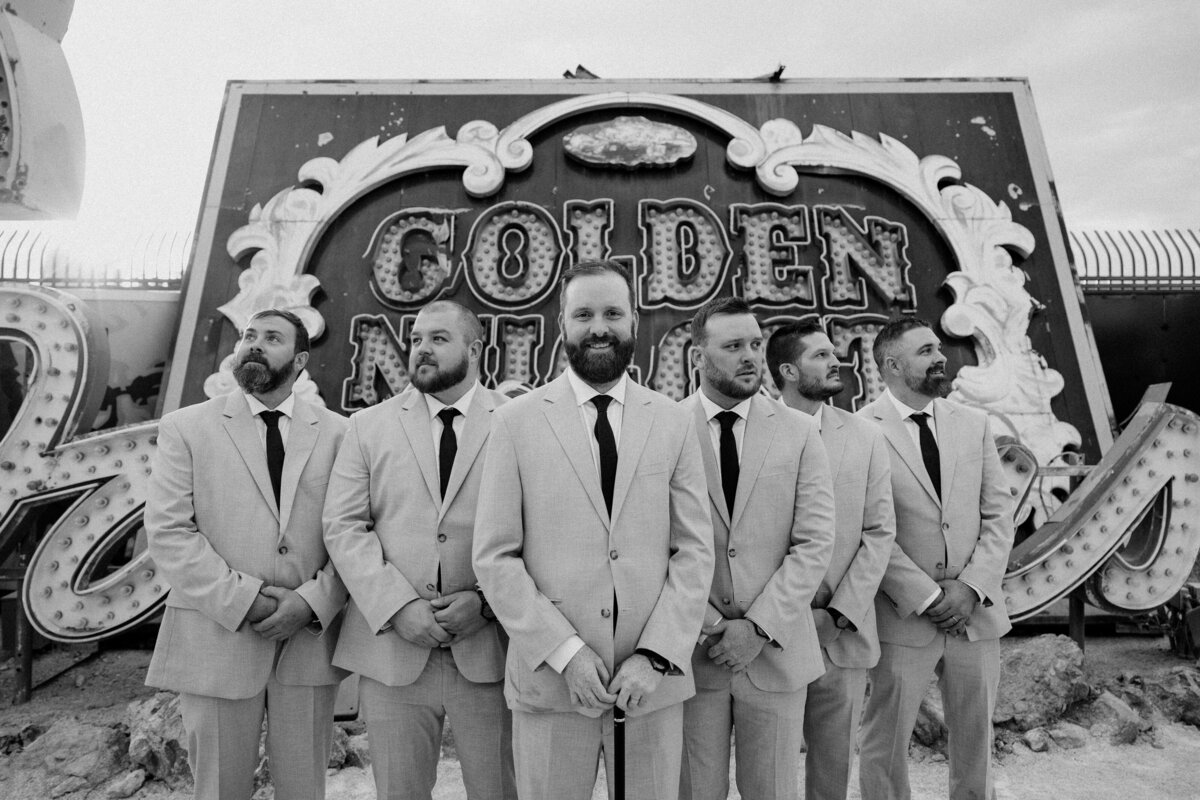 A groom poses with his wedding party in front of the old Golden Nugget sign at The Neon Museum in Las Vegas.