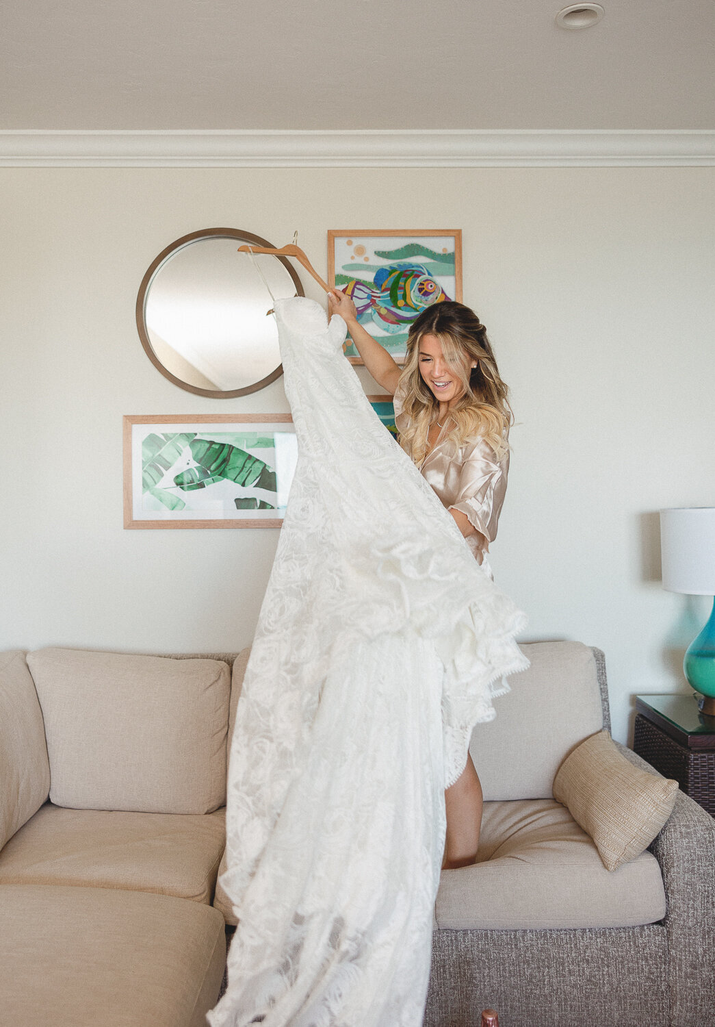 Bride Laura excitedly holding her wedding gown in her suite at Cheeca Lodge Resort, photographed by Claudia Amalia.