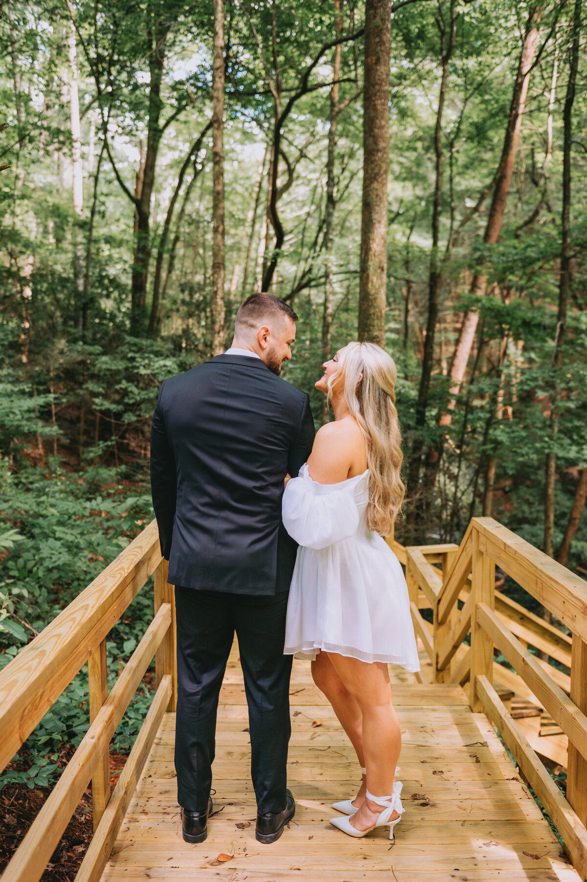Newlyweds hug one another in a forest