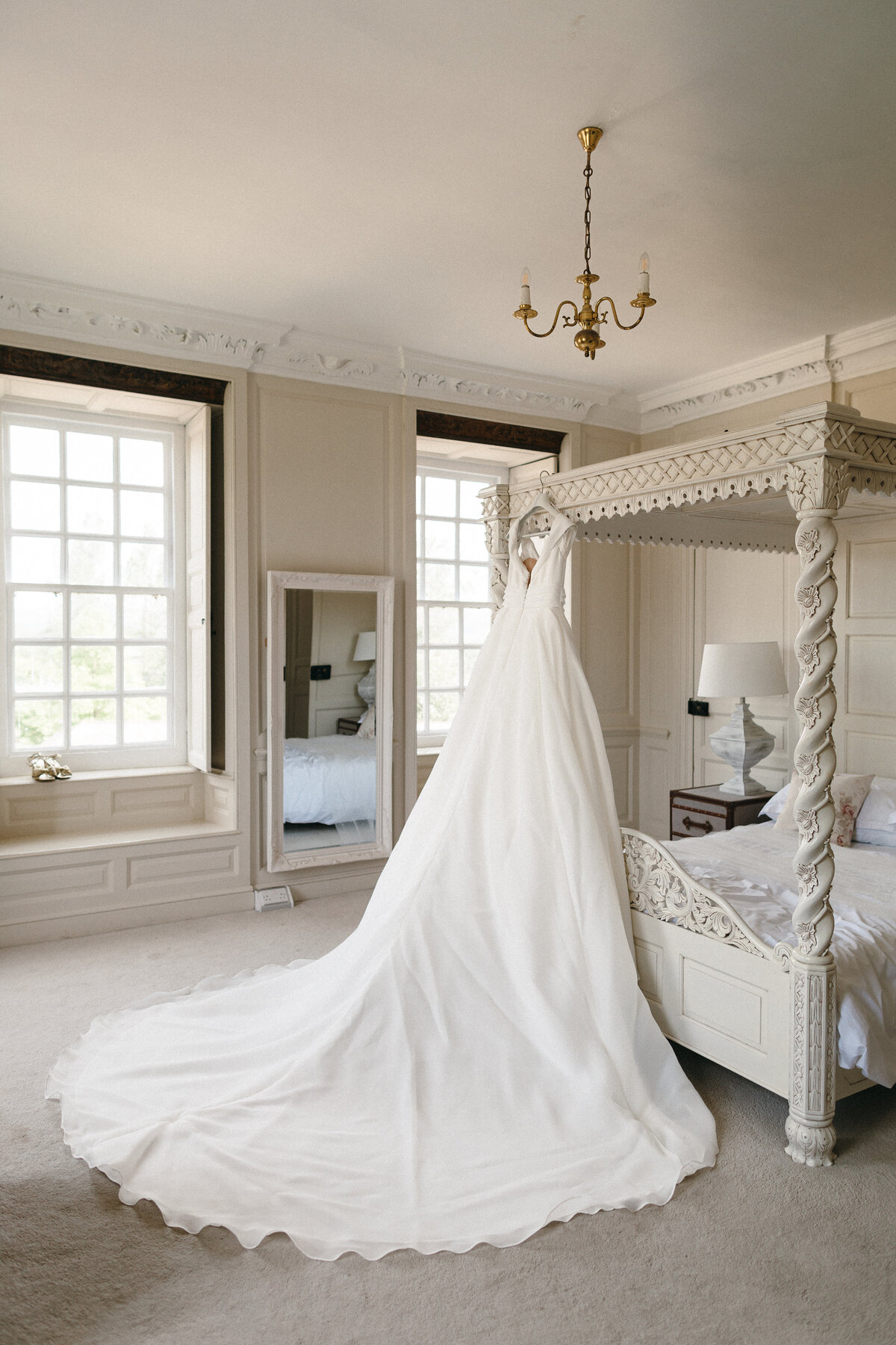 Wedding dress hung on four poster bed at Kingston Estate in Devon 