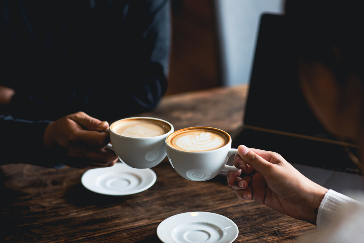 Two hands clinking cups of coffee
