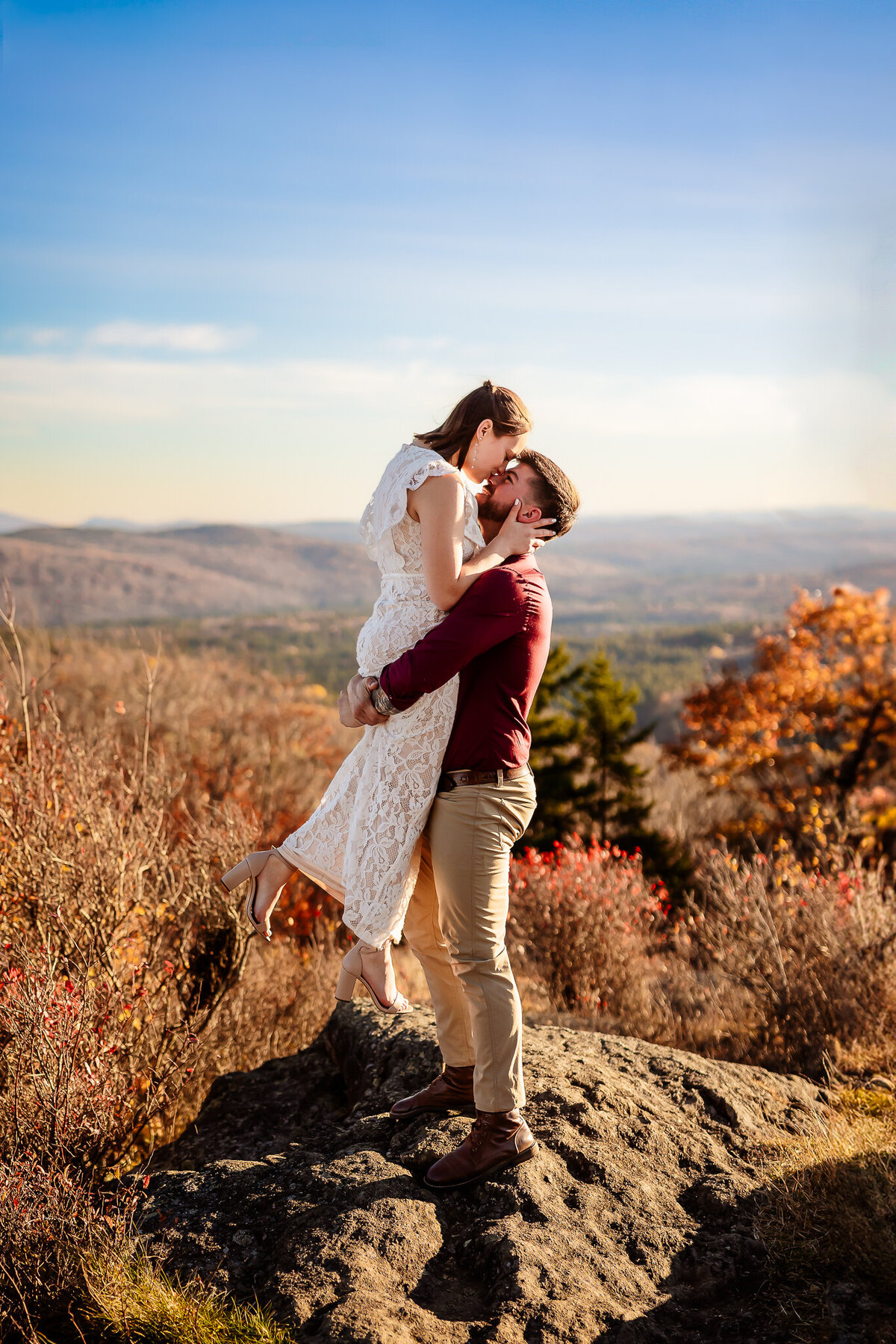 Couple kissing on rock on the summit of NH mountain by NH Wedding Photographer Lisa Smith Photography