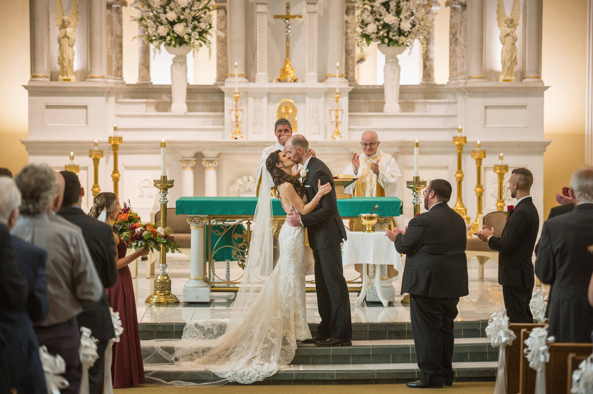 Groom kissing bride during ceremony at Saint Patrick church in Erie PA.