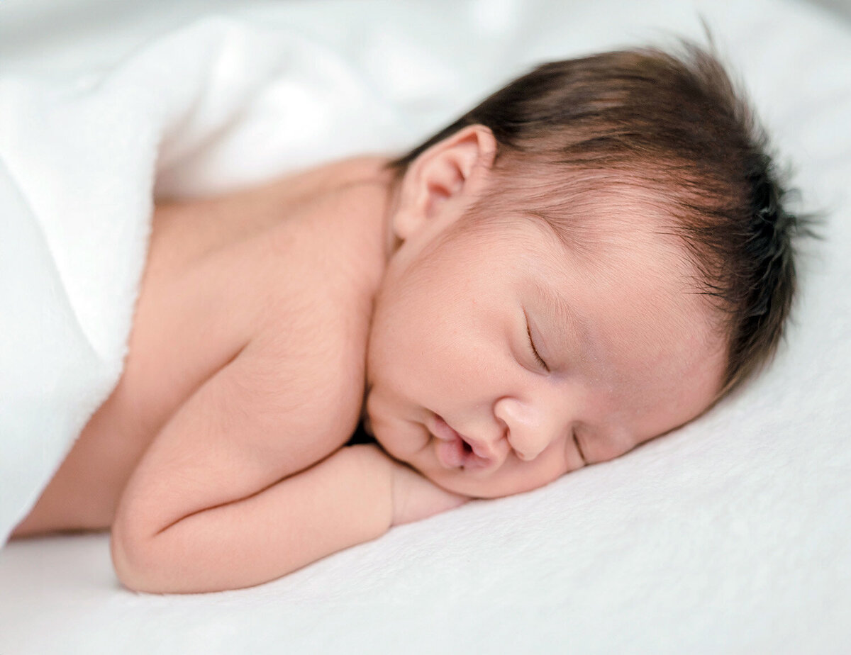 Sleeping newborn on bed with natural window light — San Francisco Bay Area natural newborn photographer