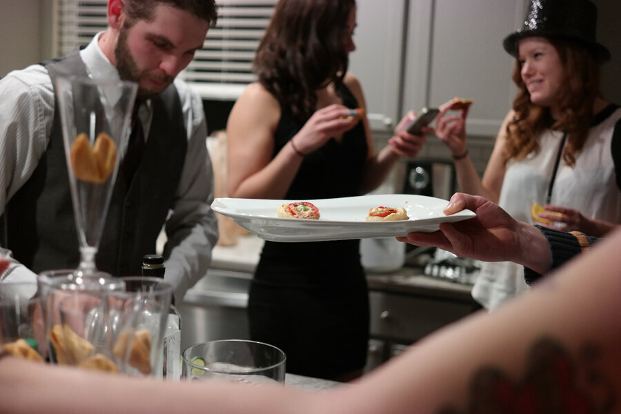 White appetizer plate getting passed around a busy kitchen.