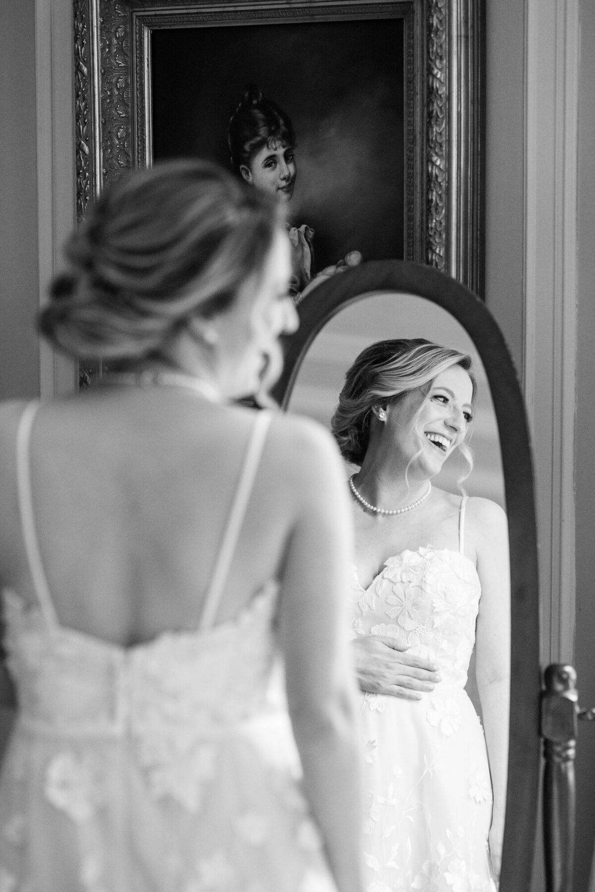 A bride is reflected in the mirror as she laughs and looks to the right