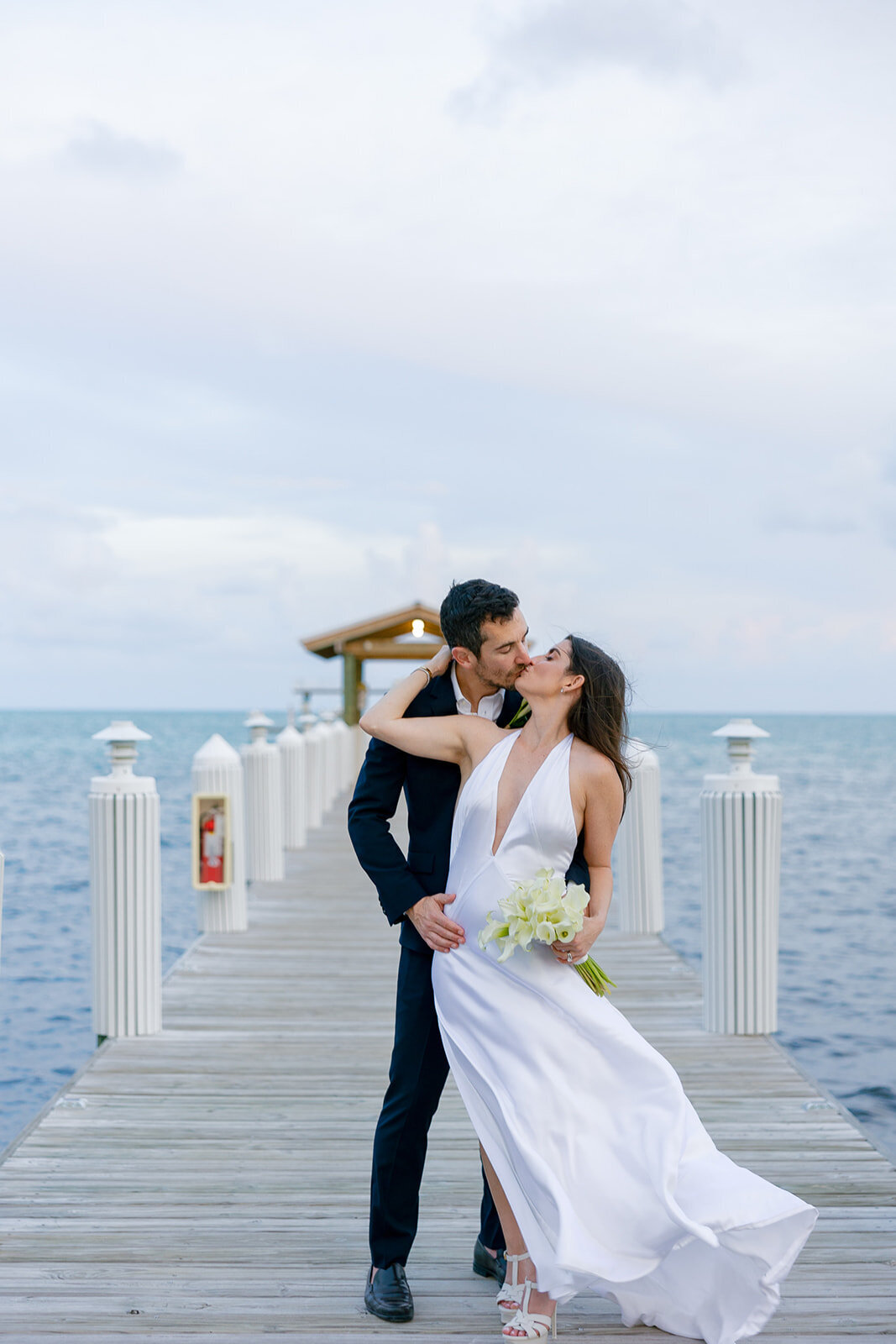 A romantic sunset moment as Minette and Evan embrace on a pier overlooking the ocean. Florida Keys micro wedding by Claudia Amalia Wedding Photography.