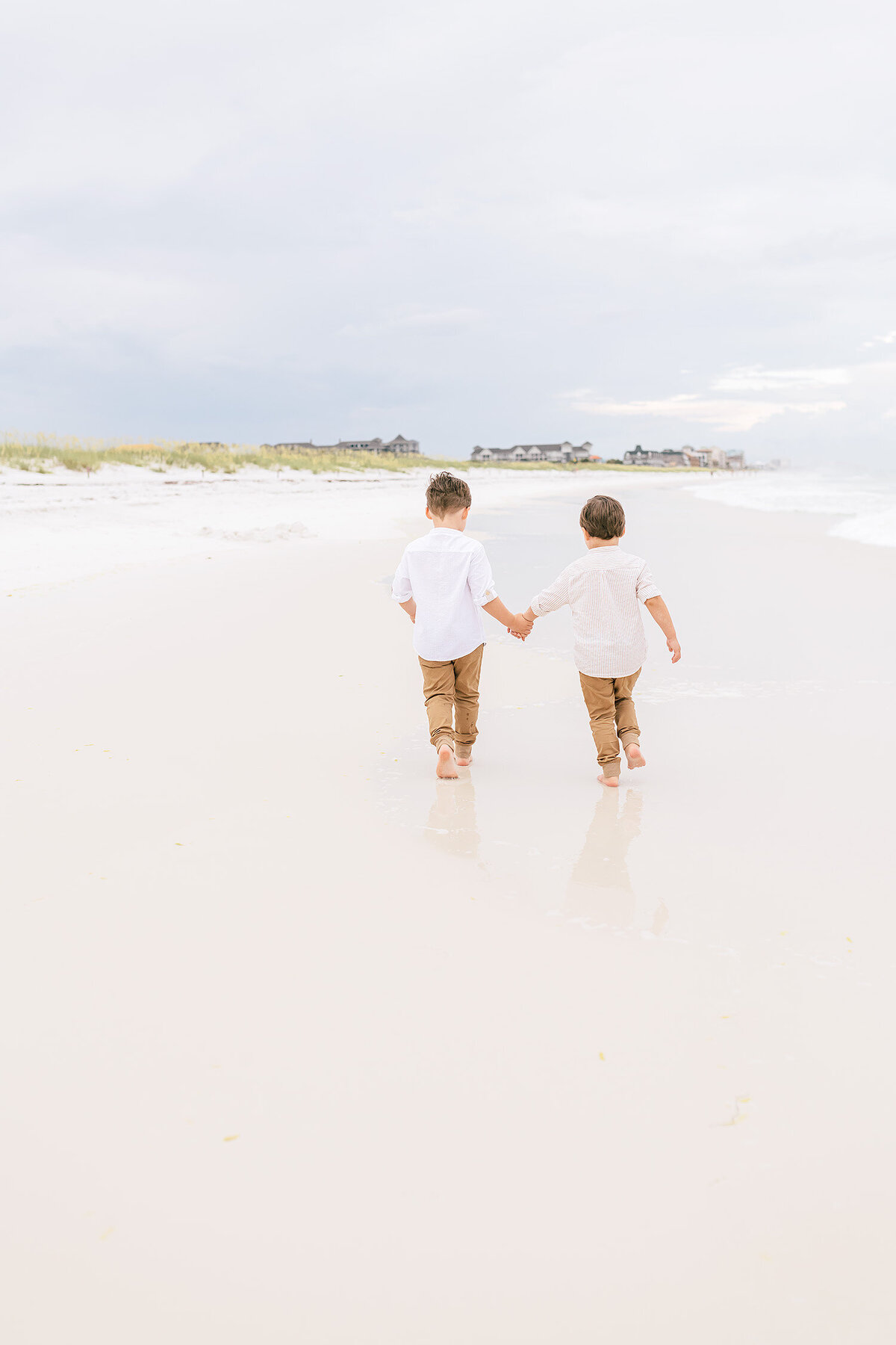 two little boys running along the beach