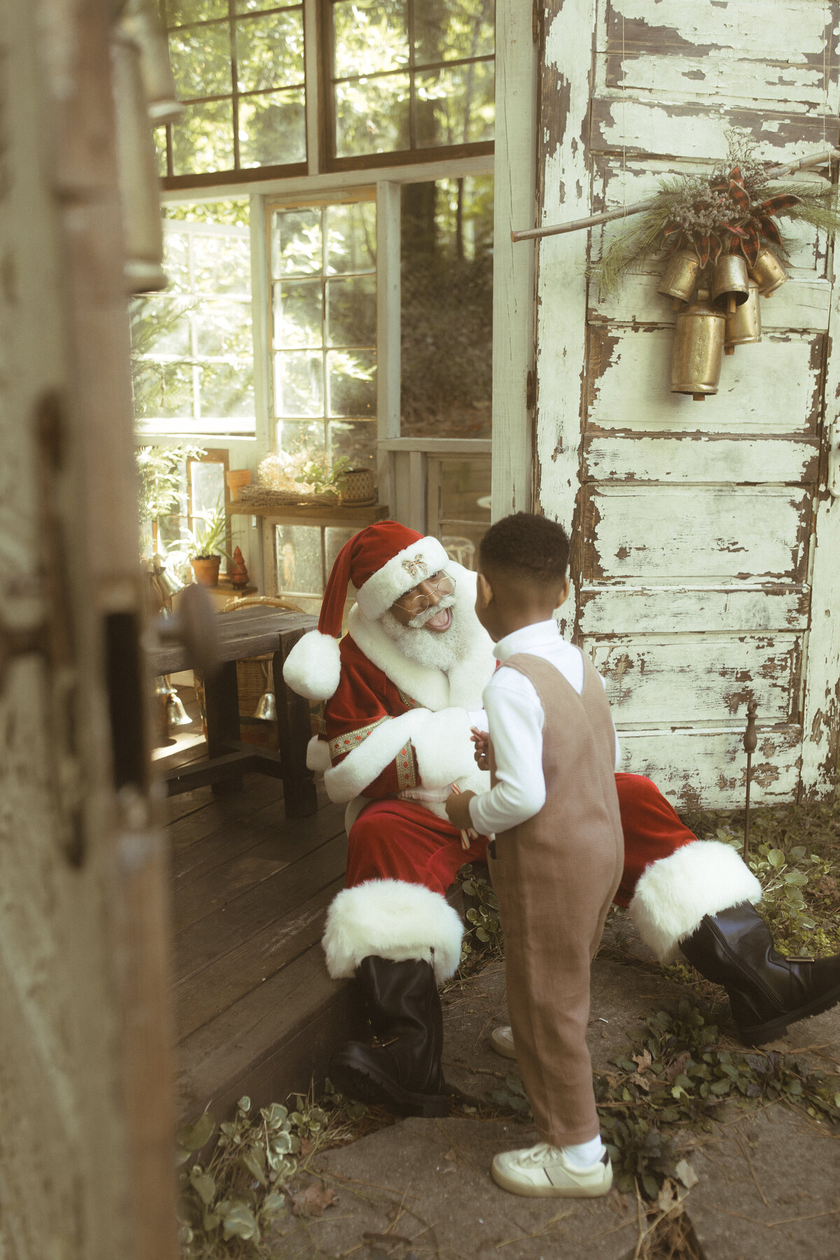 The Black Santa of Atlanta laughing with a young boy at Das Hinterhaus. 
