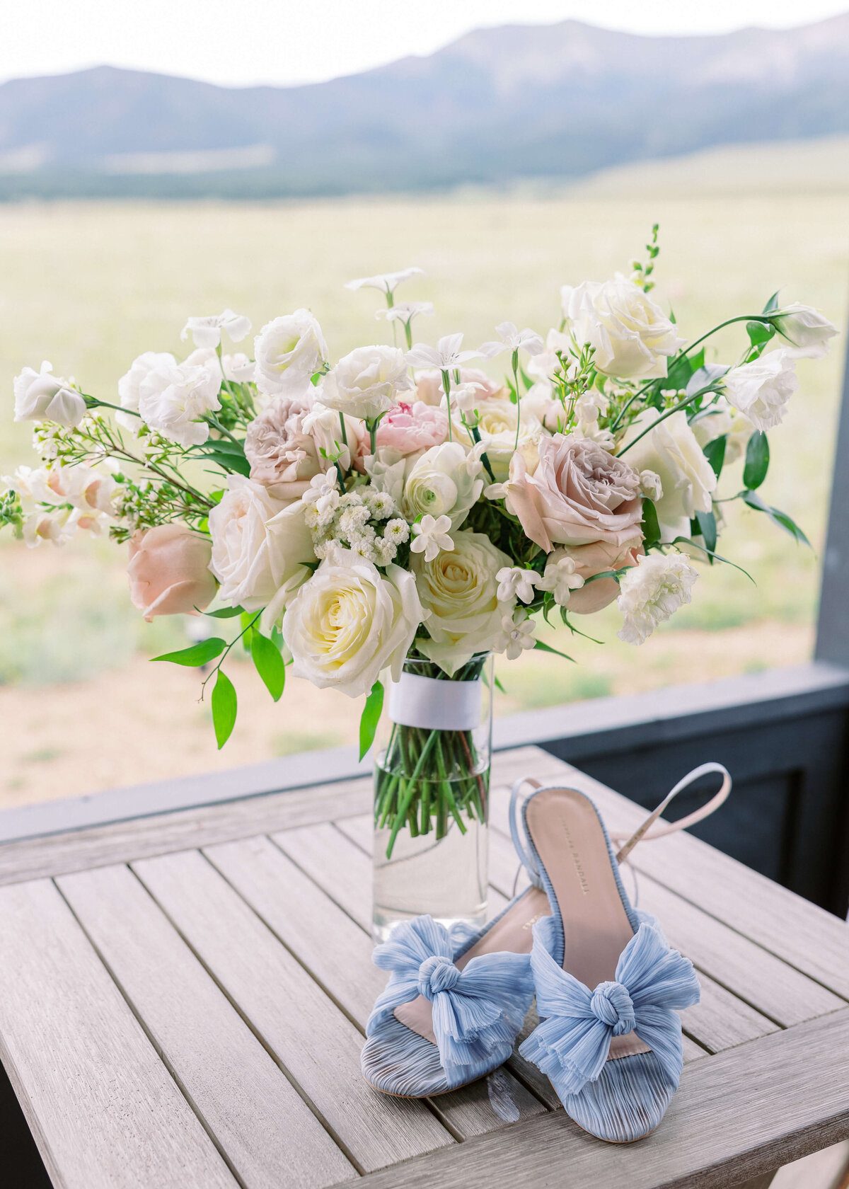 White, pink and beige florals complement the bride's light blue shoes through a palette of pastels