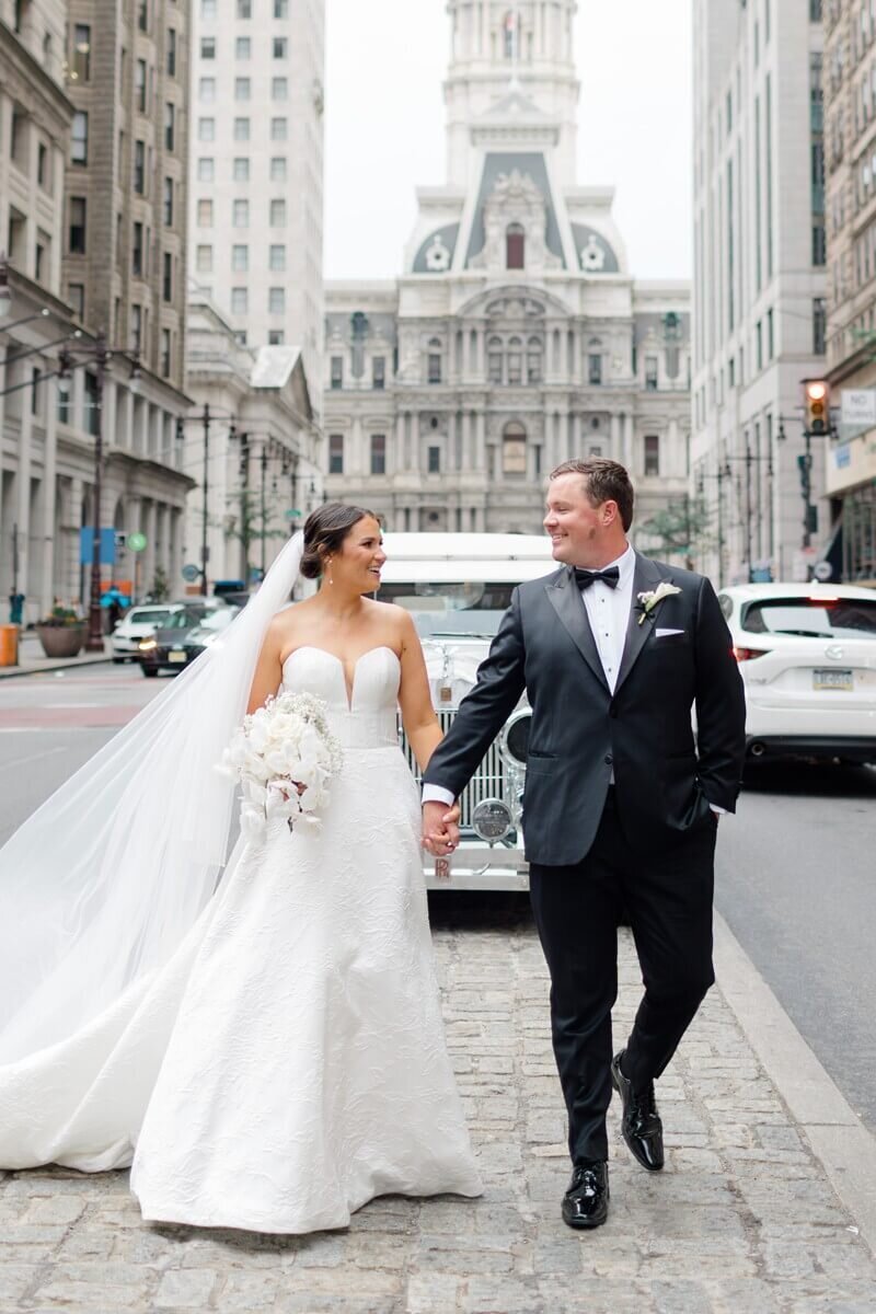 bride and groom walking median in front of philadelphia city hall