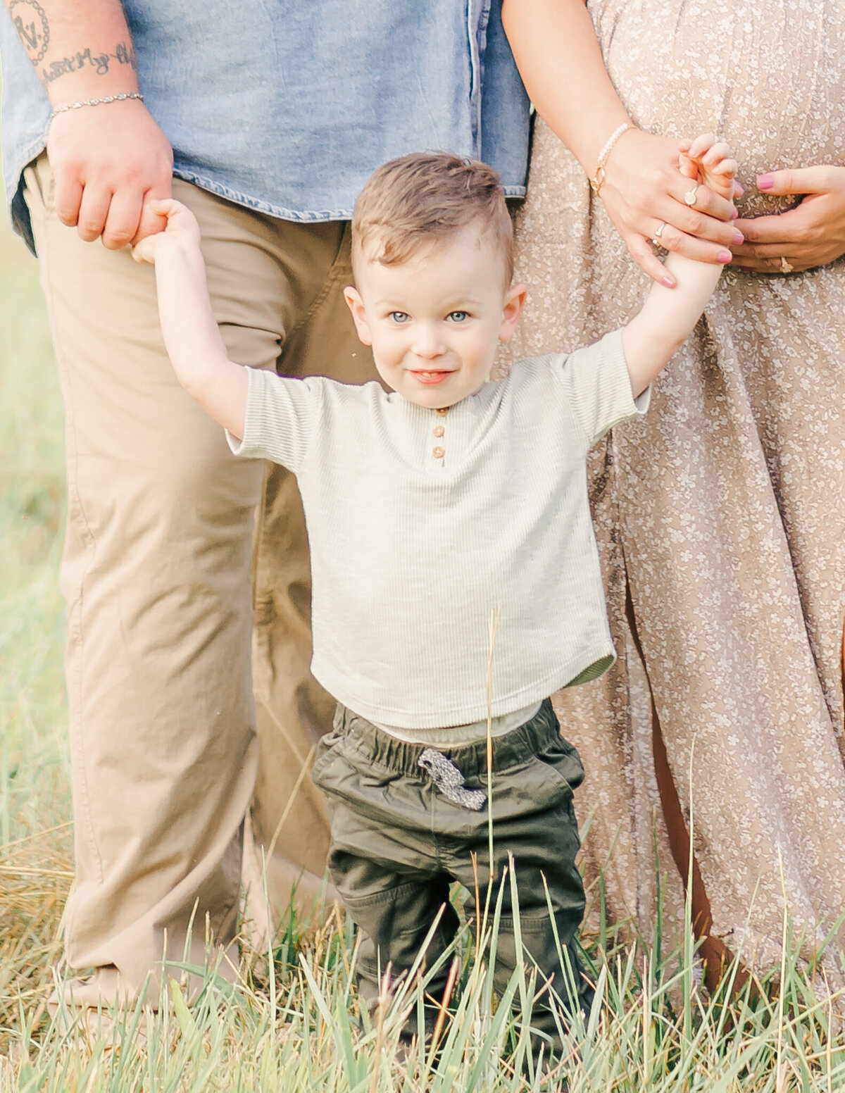little boy standing with parents in a field in middle tennessee while holding their hands