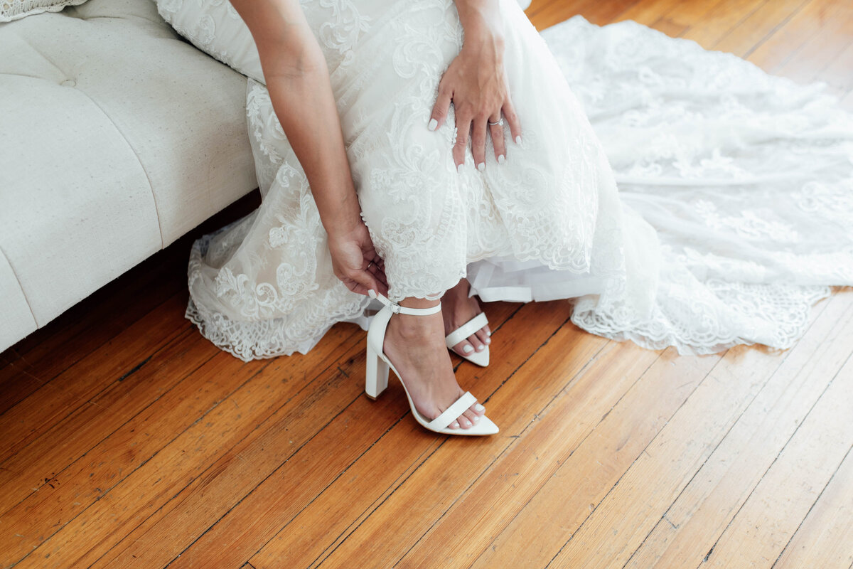 Close up of bride putting on shoes. 