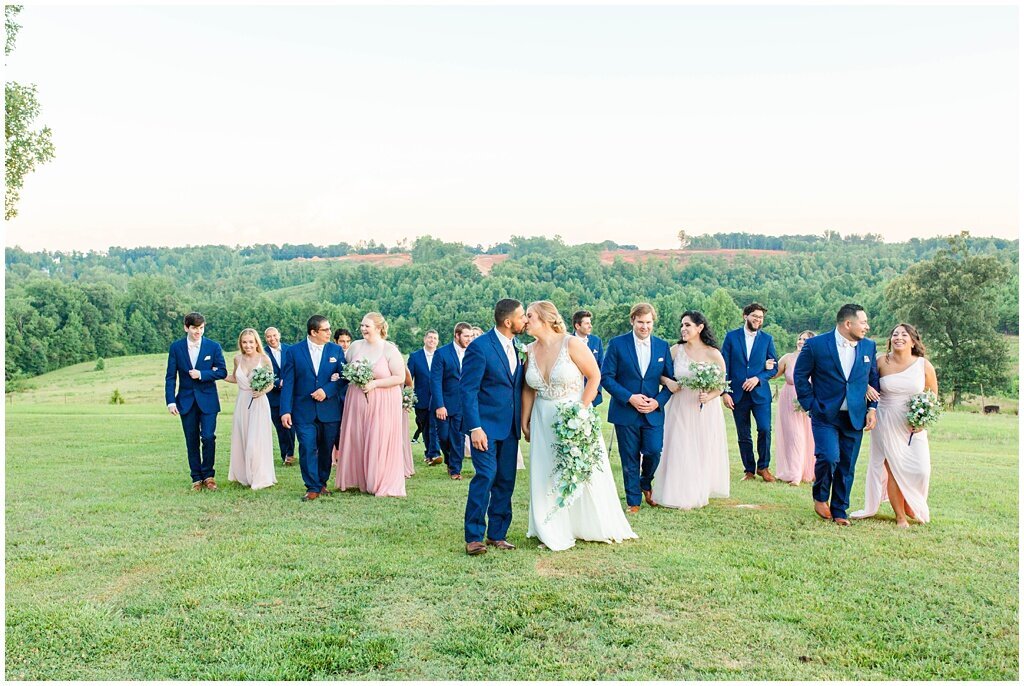 bridal party with navy and pink dresses walking up a hill together