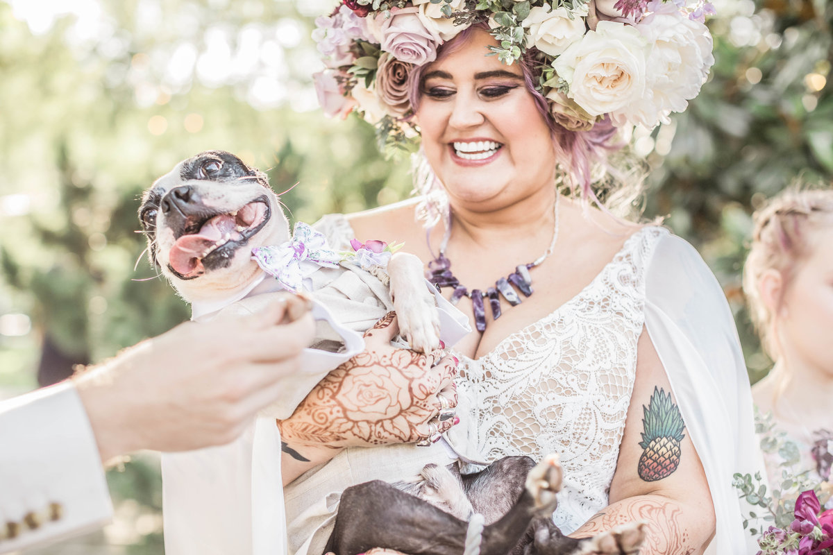 Bride with flower crown smiles and holds pet dog at Haiku I do in Asheville North Carolina