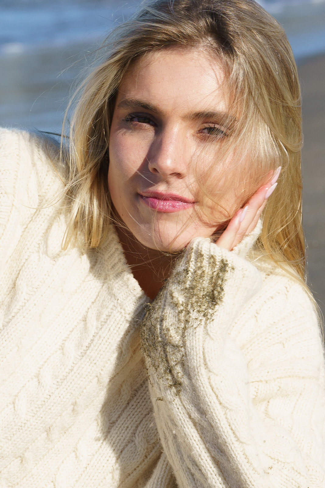 Close up of an attractive woman laying on the beach in a wet sweater
