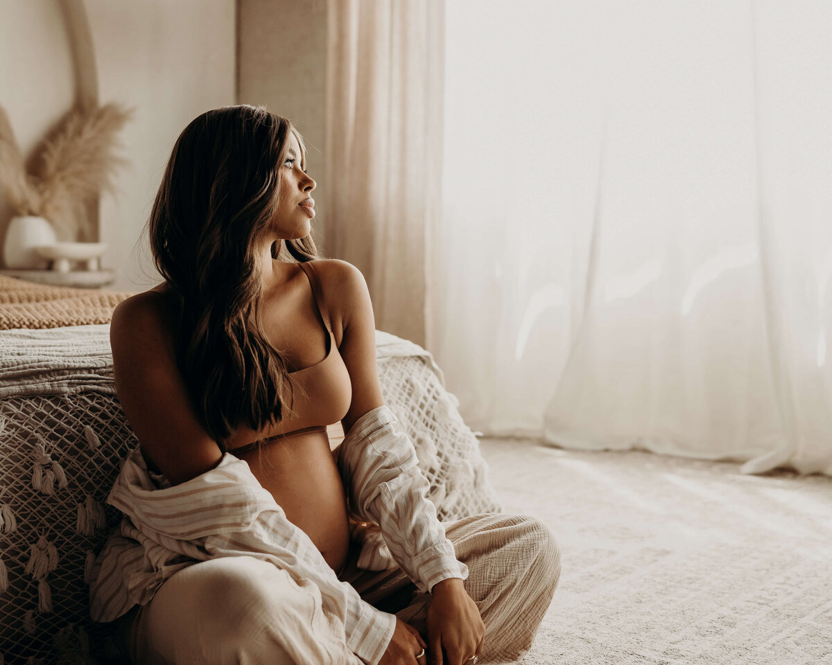 pregnant woman sits crosslegged in striped linen lingerie