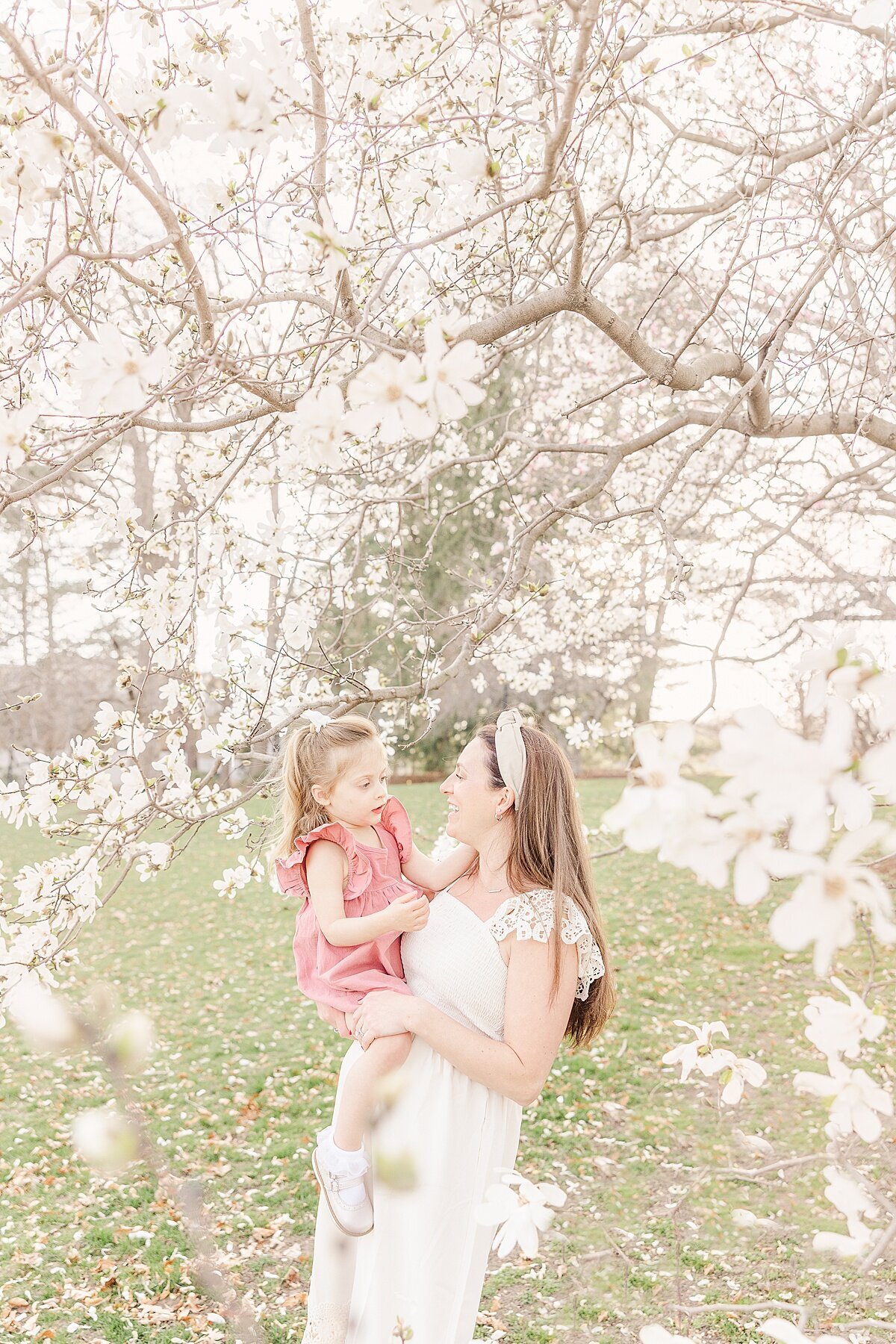 mom holds daughter during spring maternity photo session in Wellesley Massachusetts with Sara Sniderman Photography
