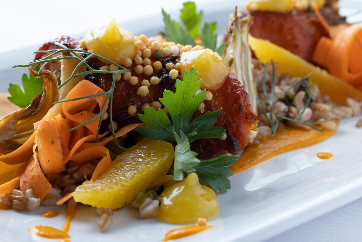 Orange-glazed protein with citrus segments and herbs