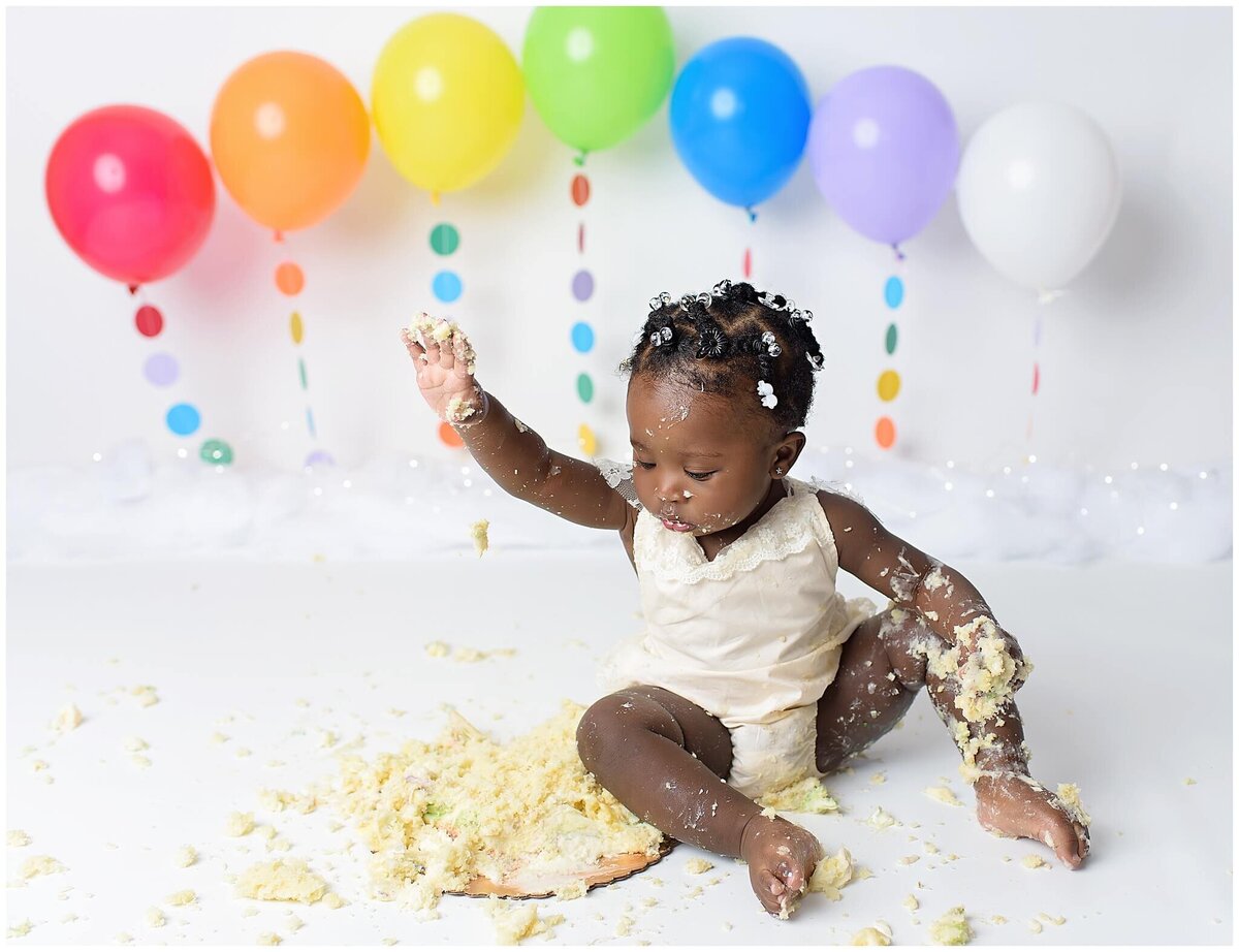 A messy and adorable cake smash session featuring a girl covered in frosting.