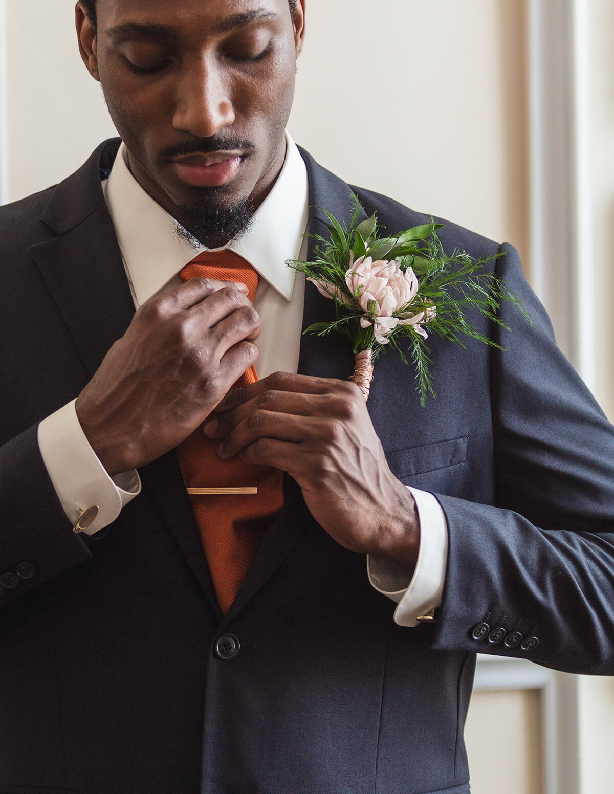 man adjusting his tie before wedding