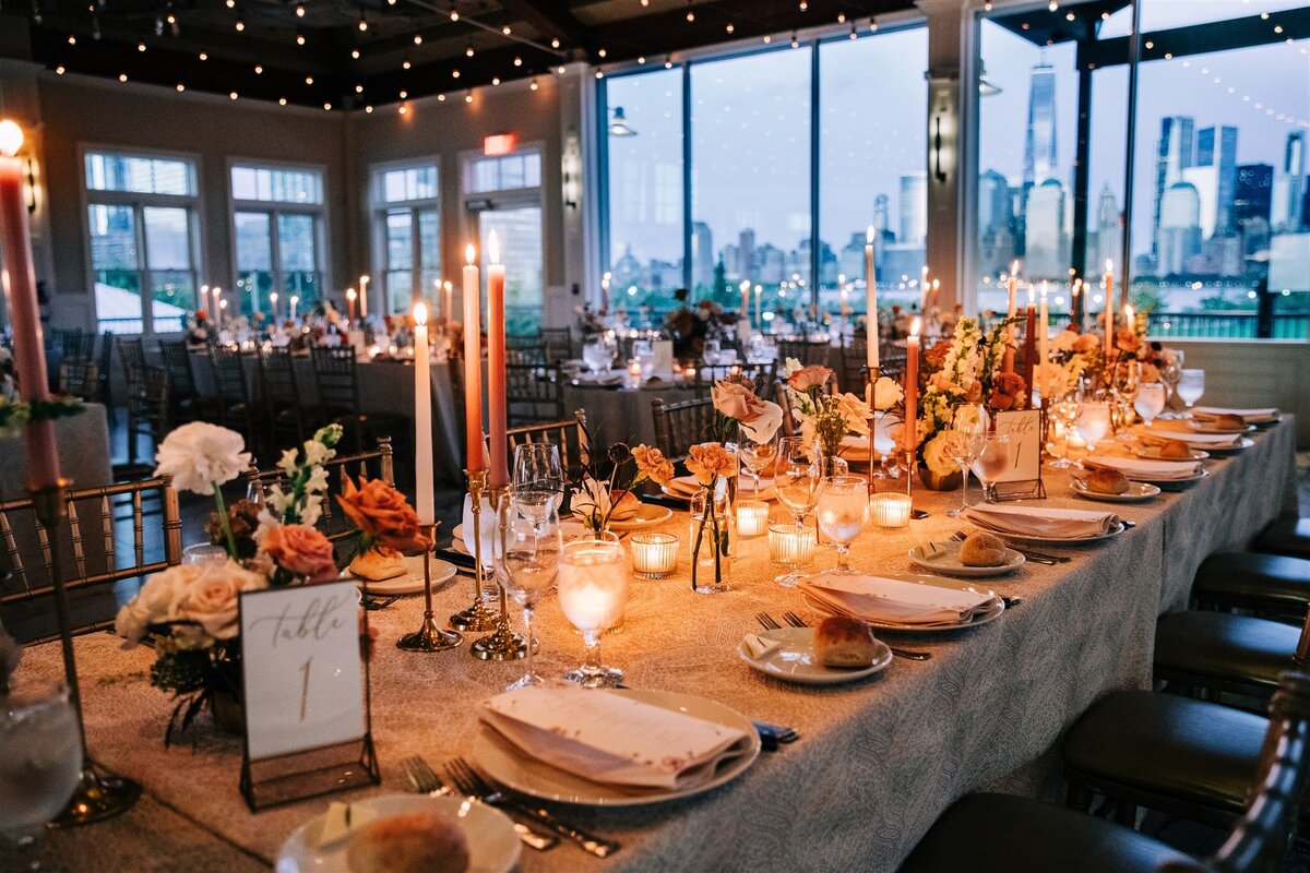 A long dining table set for a candlelit wedding reception with floral accents and ambient lighting