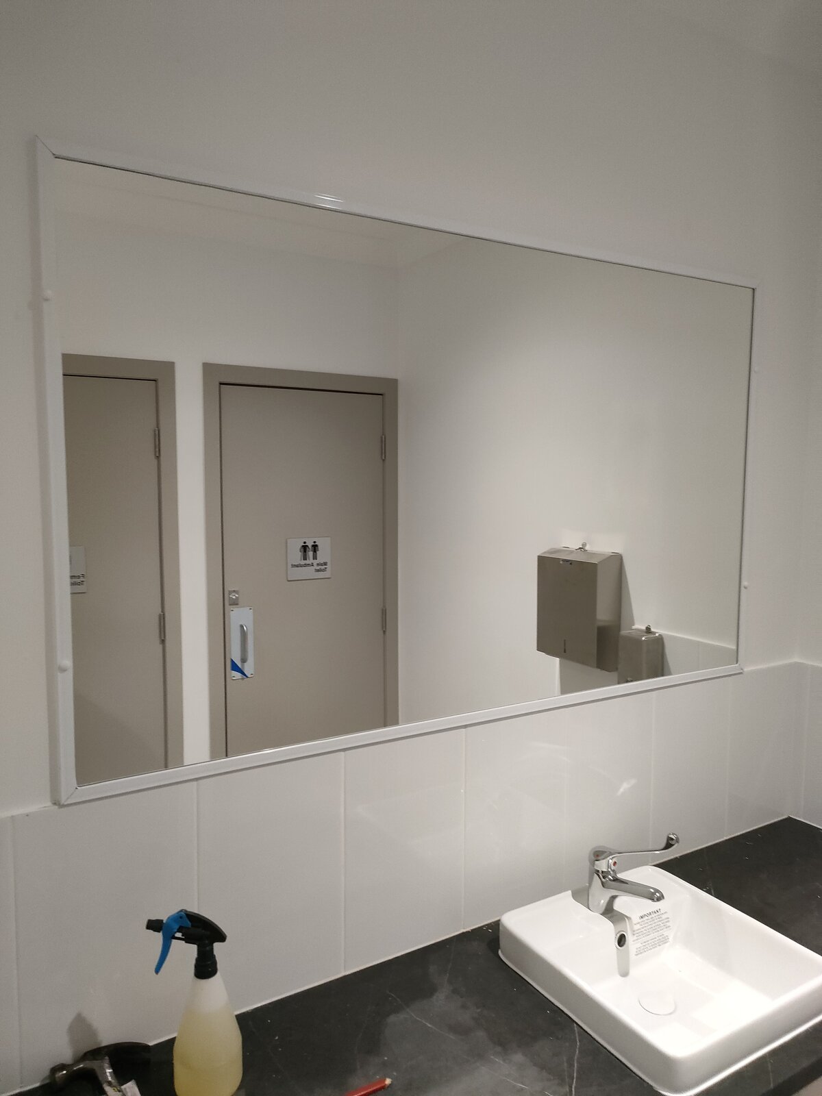 Clean restroom featuring frameless mirrors, enhancing the contemporary design.