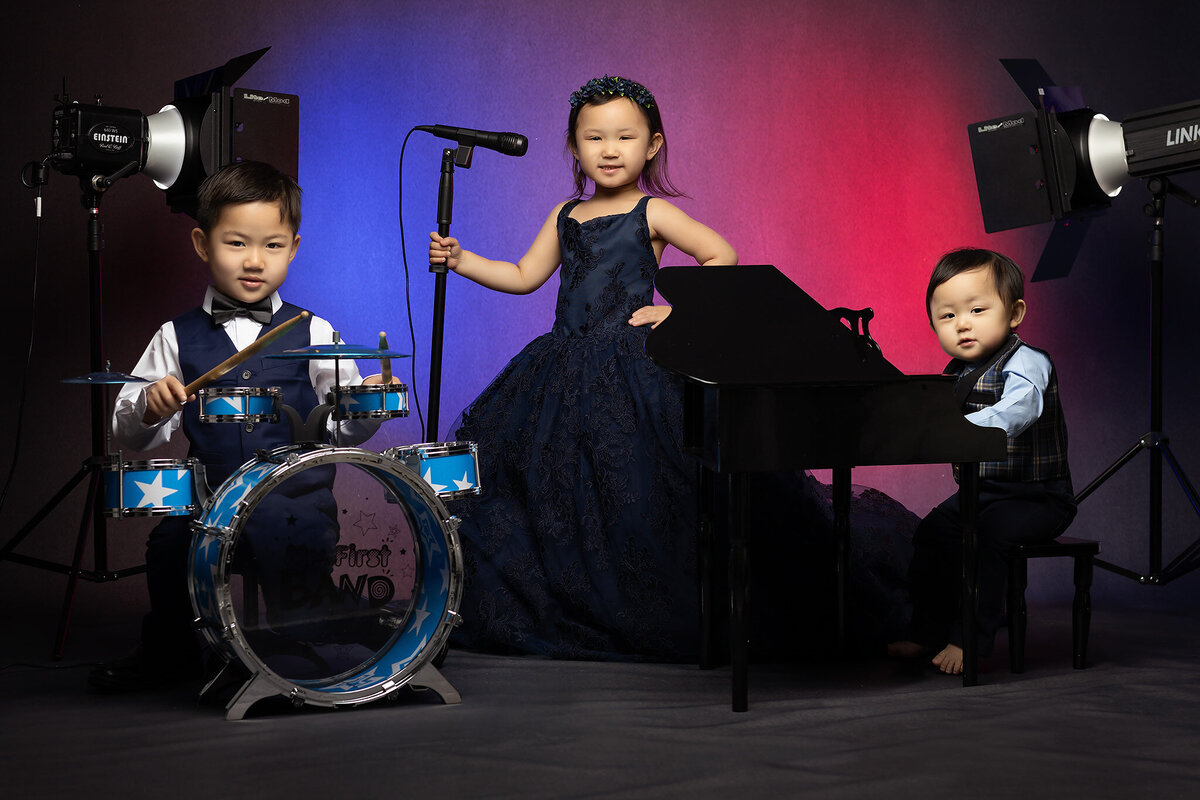 A Dallas baby milestone photographer captures a boy on drums, girl singing, and baby at the piano.