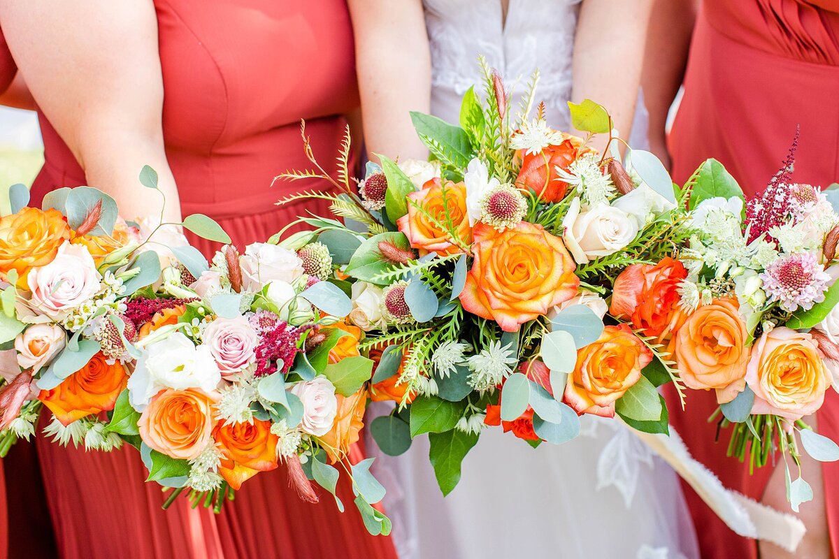 orange fall bouquets with burgandy dresses