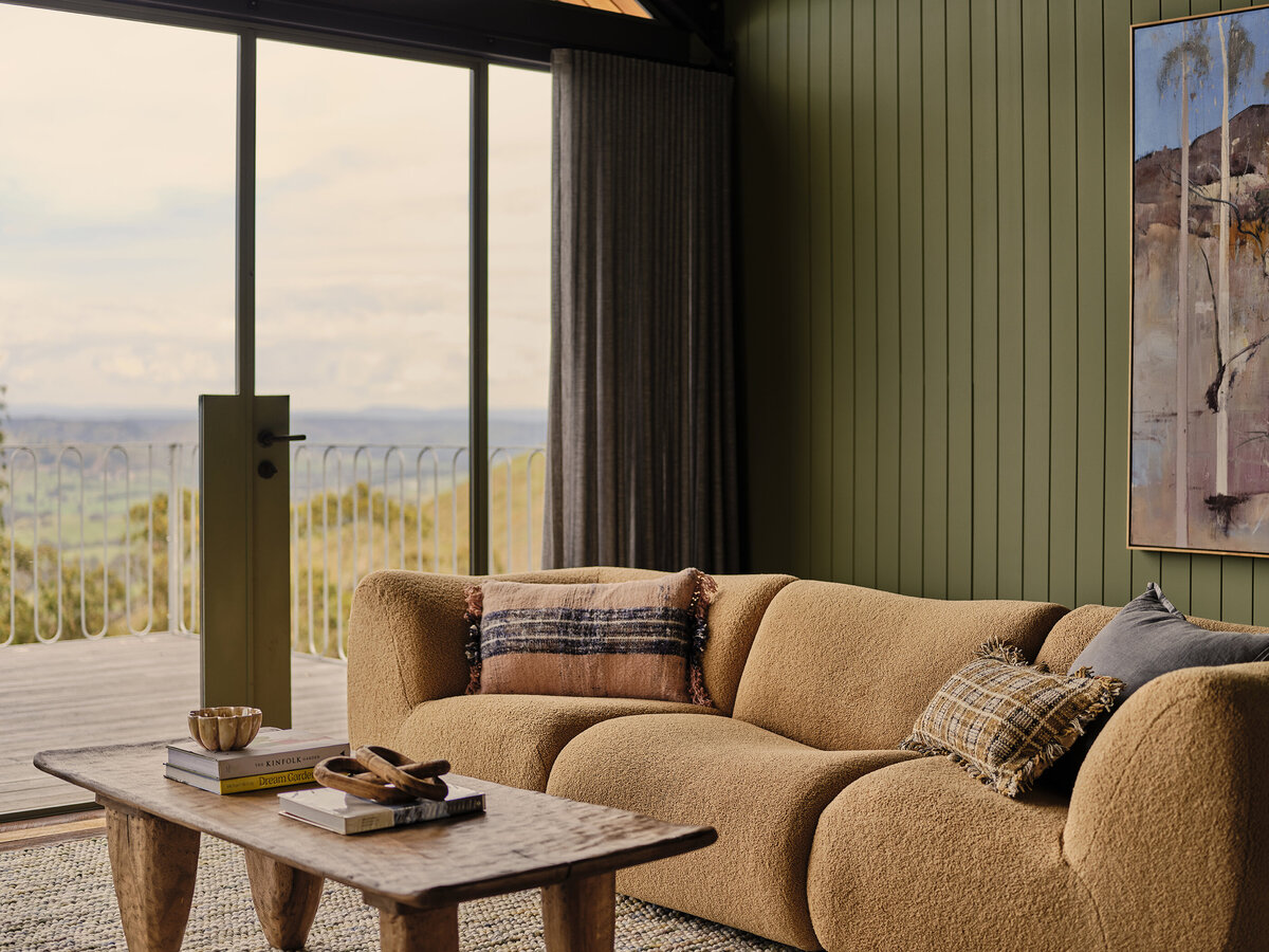 Cosy lounge with boucle sofa, timber coffee table and landscape views through glass doors, designed by Melbourne interior designer Lisa Hunter.