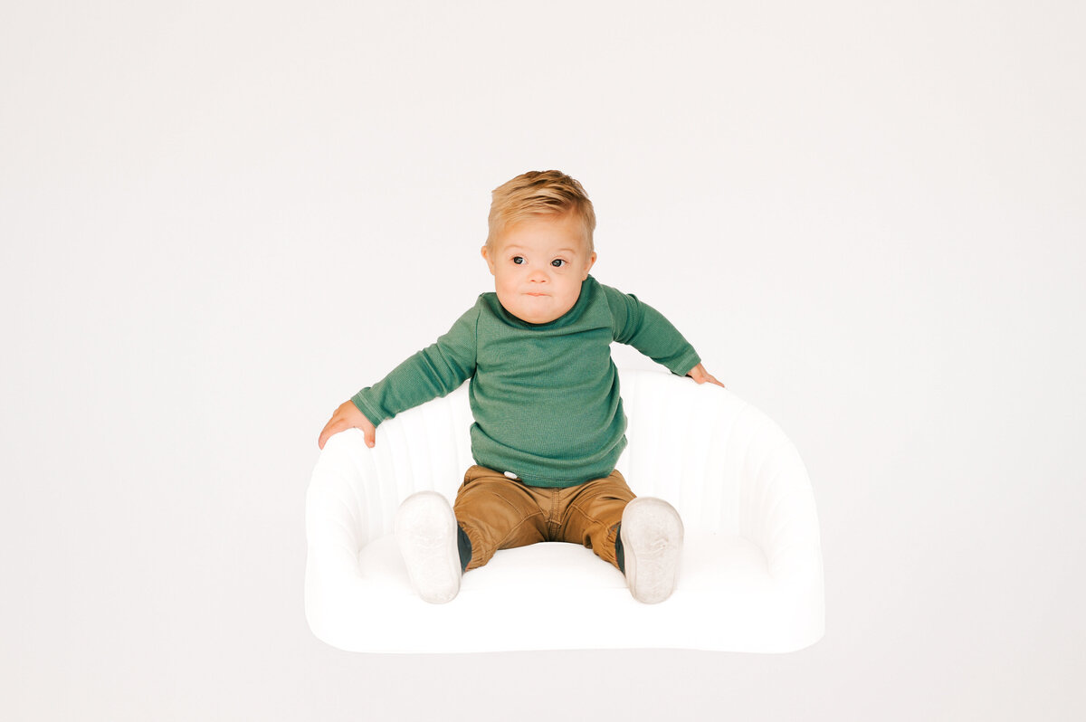 toddler boy posing on white couch during 1st birthday photography session in Springfield MO