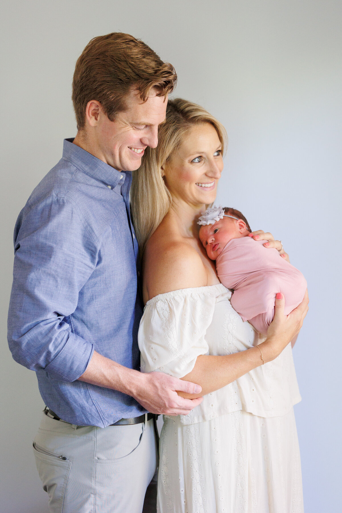 Couple looking at a window holding a newborn