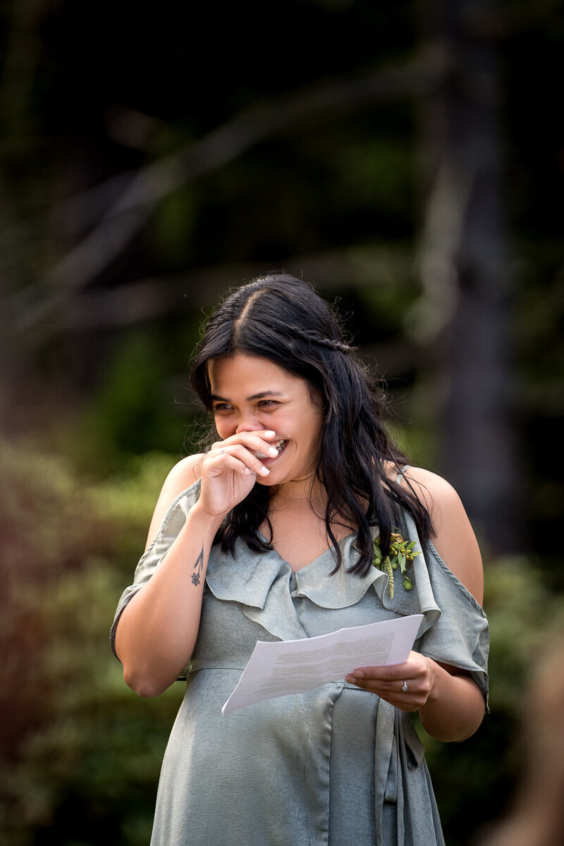 A touching moment as the Maid of Honor gives an emotional wedding speech at Ridgefield on Fickle Hill in Arcata. Surrounded by the enchanting redwoods, the bride and groom share laughter and happy tears during this heartfelt celebration. A memorable highlight of their Northern California wedding day.