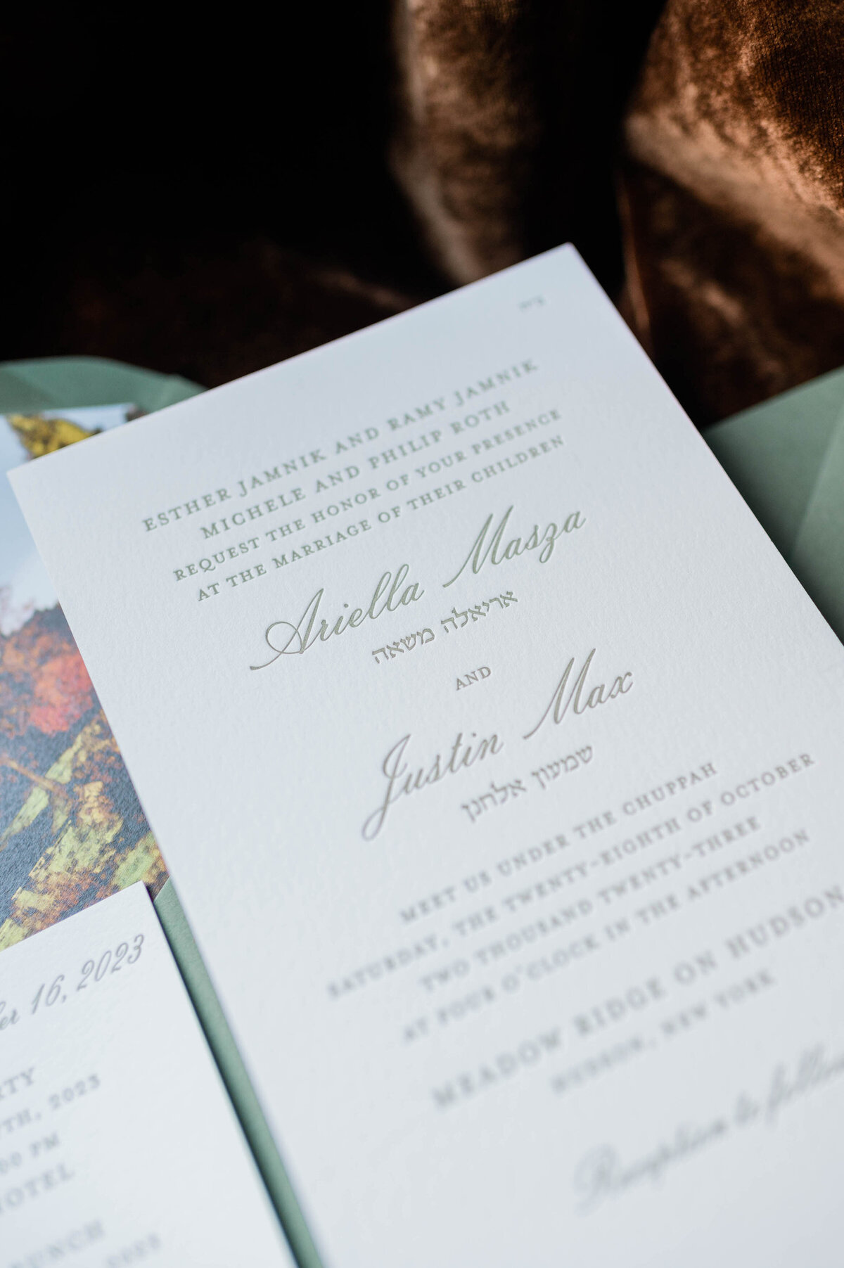 A wedding invitation printed on elegant ivory paper with soft green lettering, announcing the marriage of Ariella Mazza and Justin Max