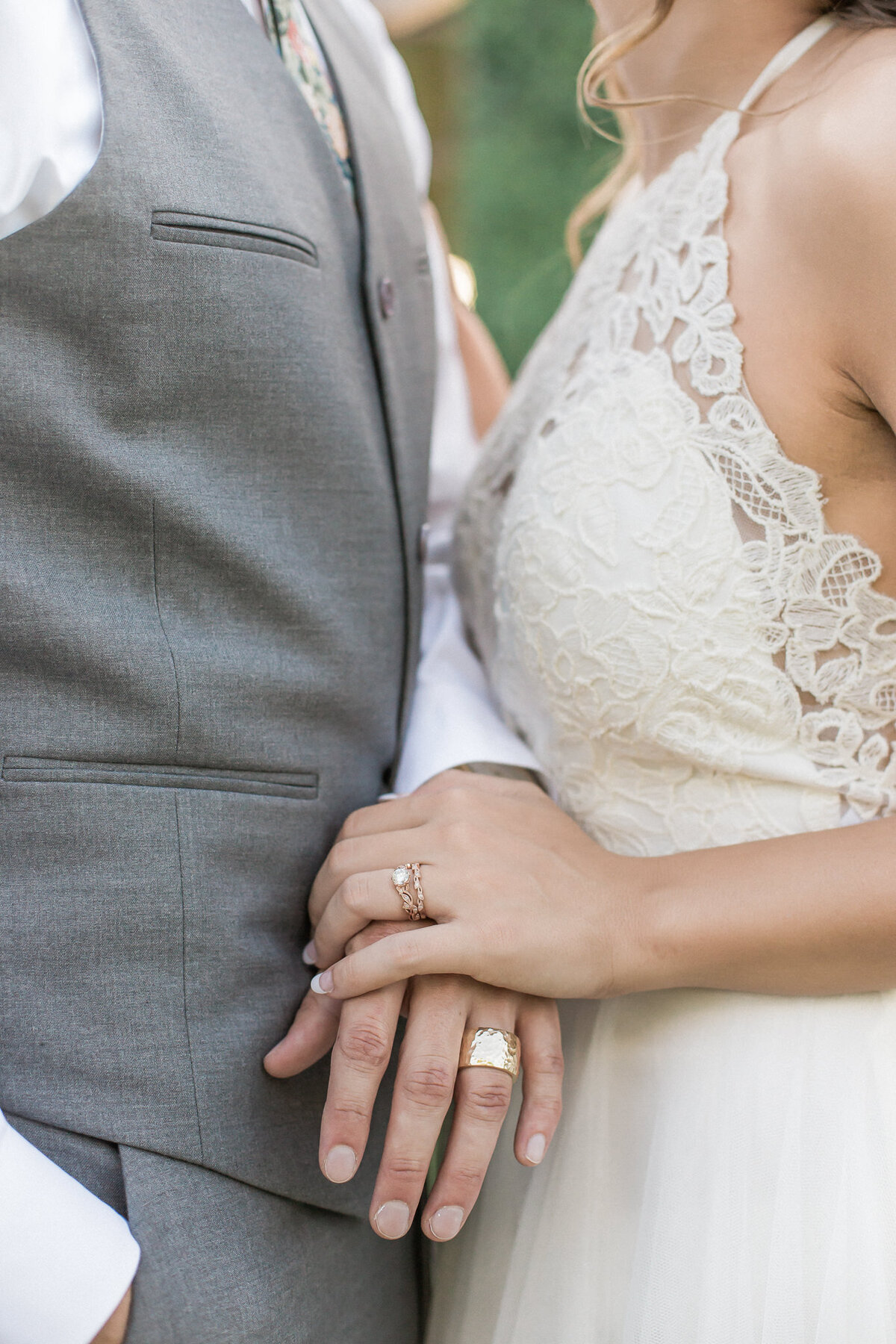 The bride and groom hold hands, showcasing their new wedding bands