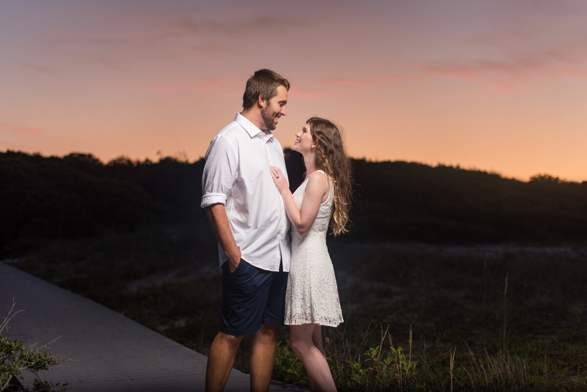 young couple embracing for engagement session at 89th street virginia beach virginia board walk