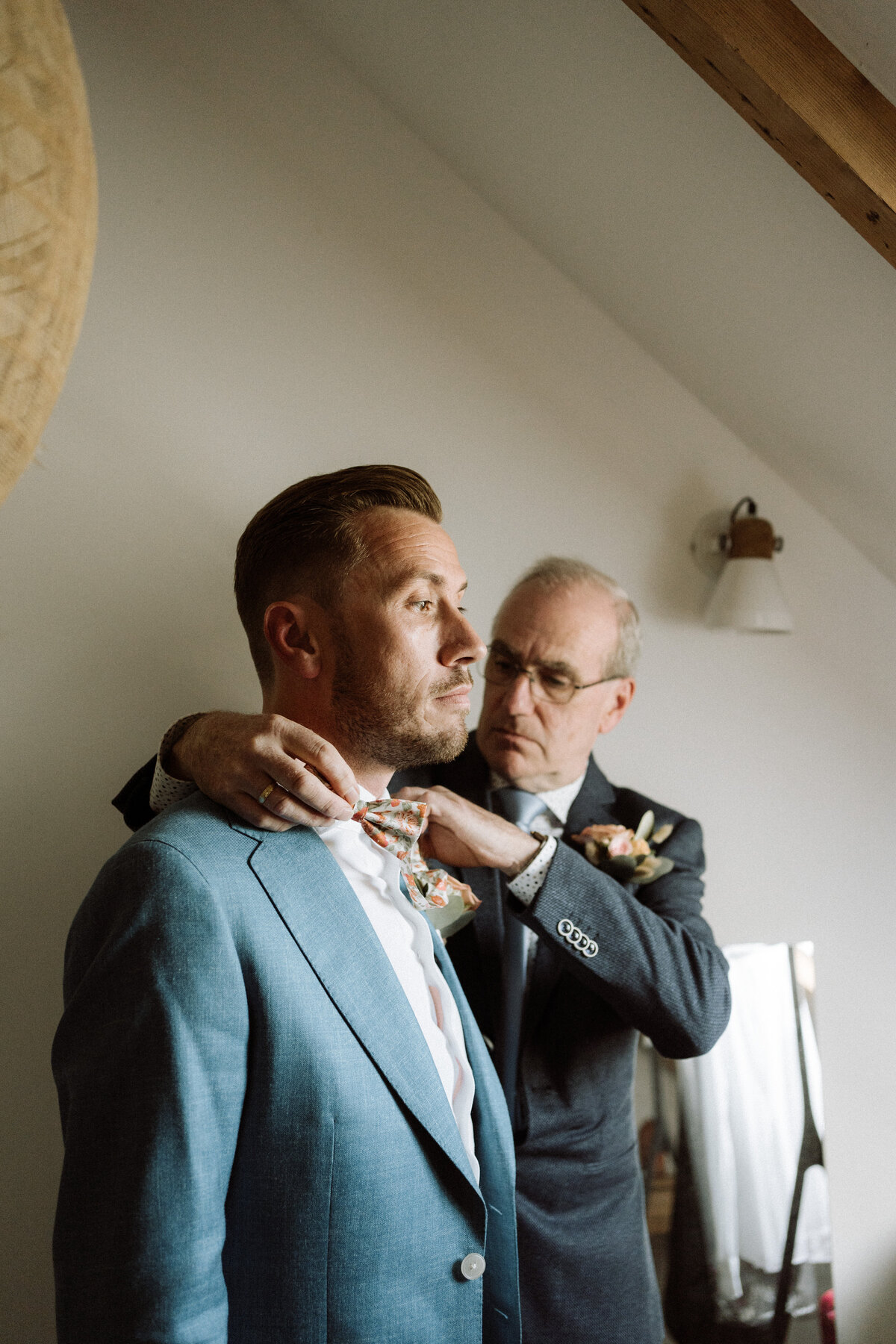 Getting ready van bruidegom, vader doet de strik goed. 