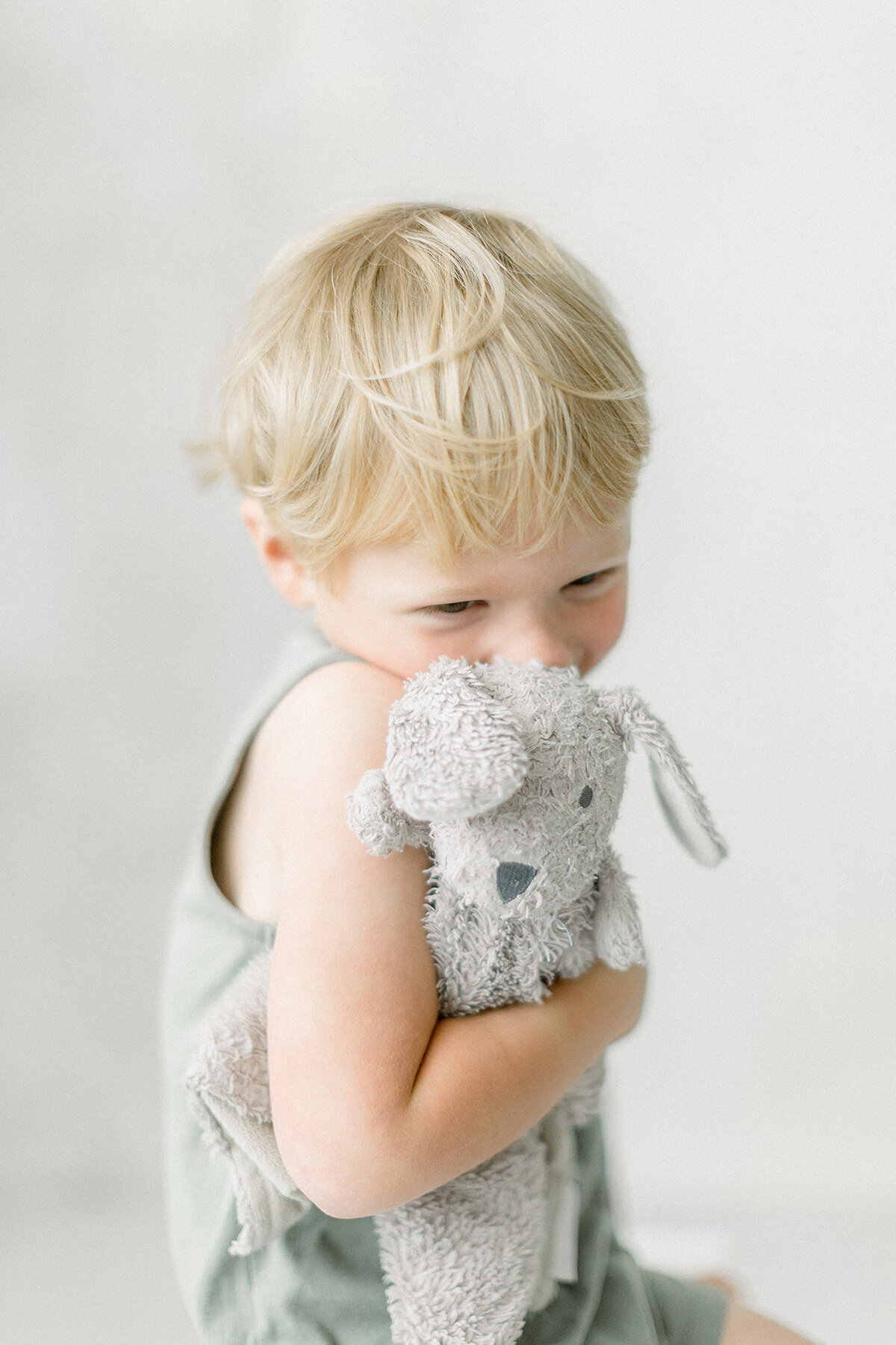 A close up photo of a little boy and his stuffed toy during his mothers maternity session taken in a Dallas/Fort Worth photography studio.